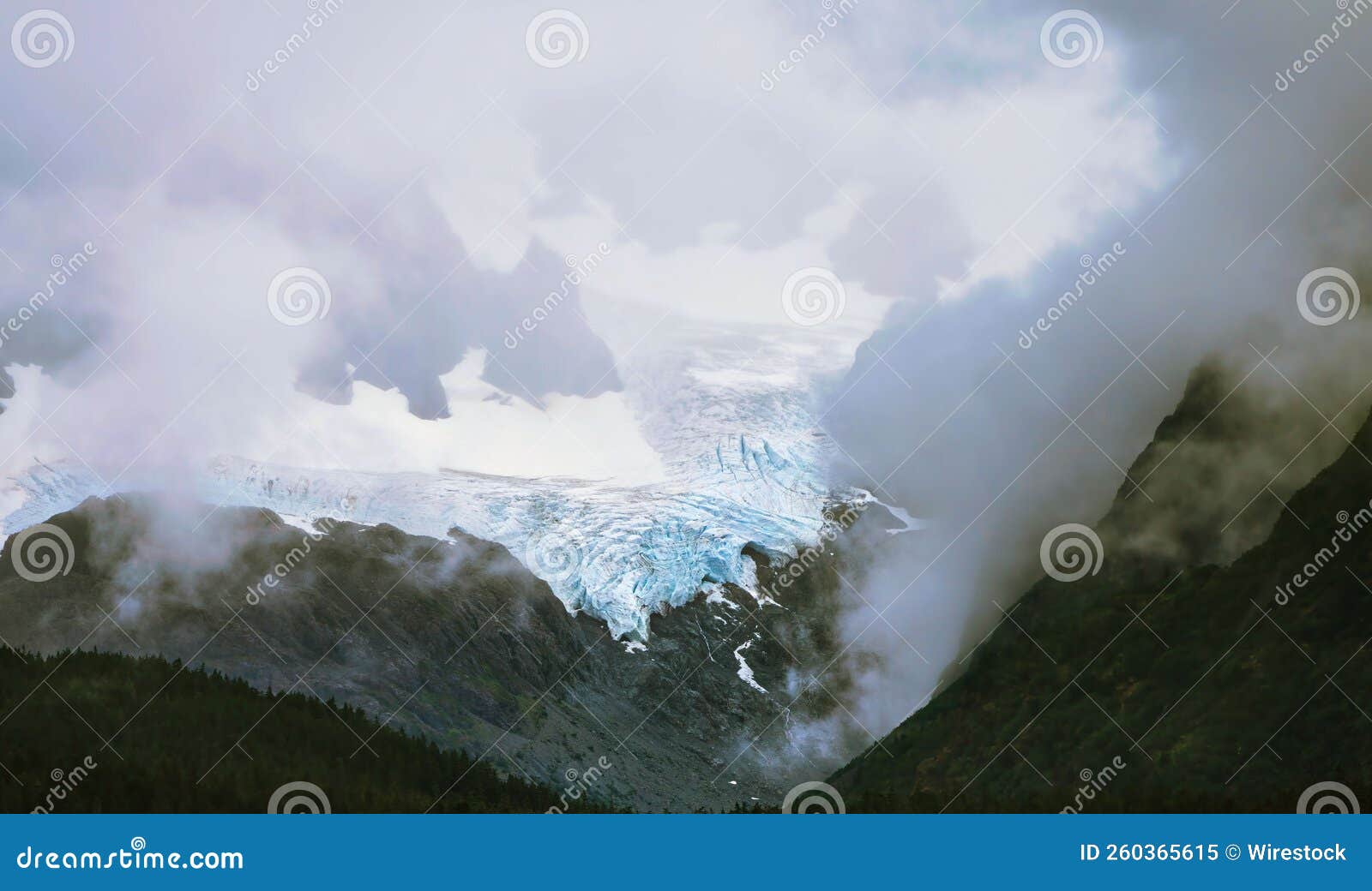 scenic view of godwin glacier with low hills enveloped in fog in alaska