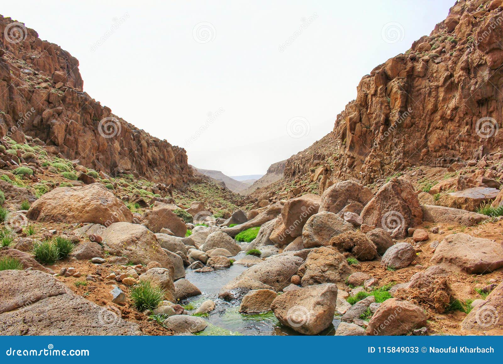 scenic view of mountain cliffs and a stoney river in the middle.