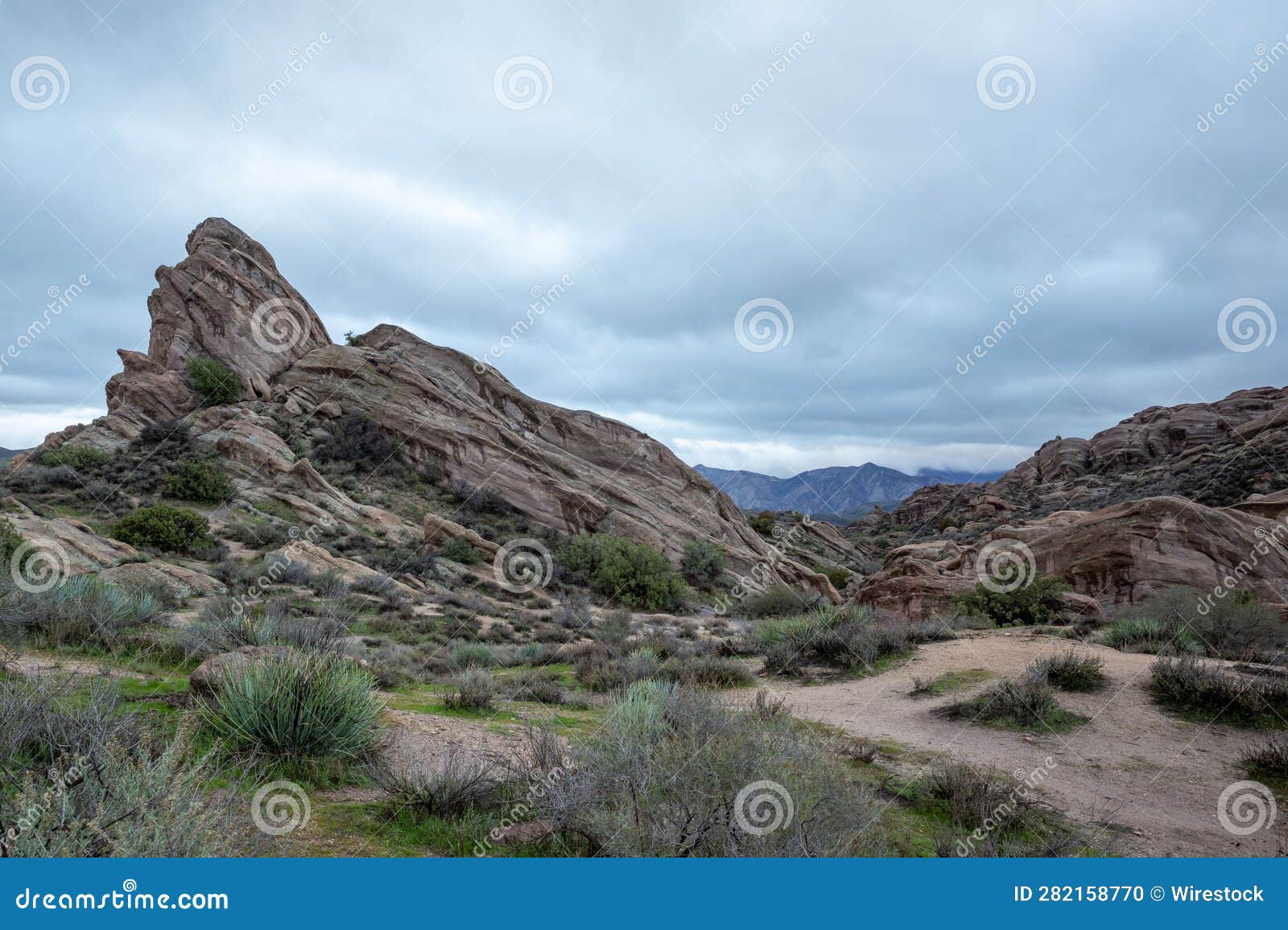 scenic view of vasquez rocks park in agua dulce, california with bushes against a clouded sky