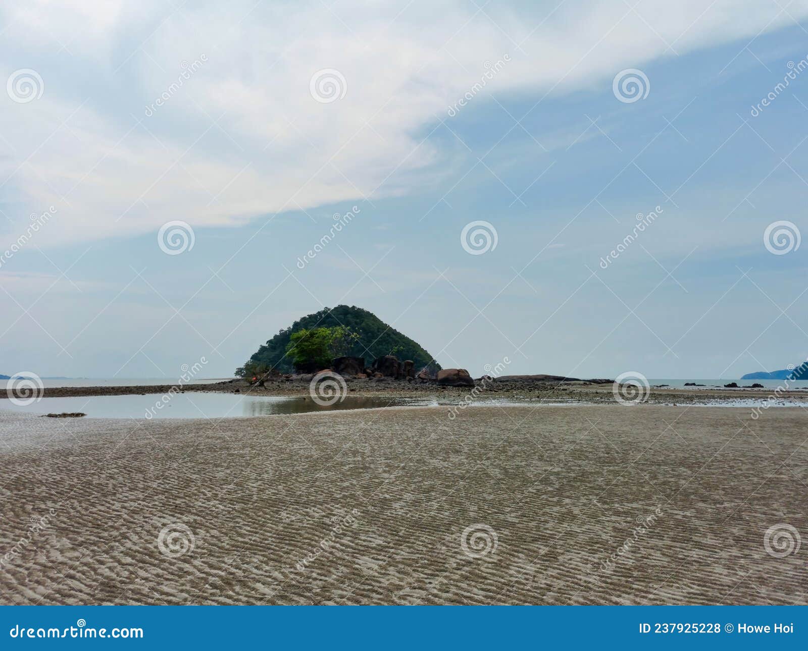 scenic wide angle view of small tropical island at low tide sandy beach with cloudy sky in endau, malaysia