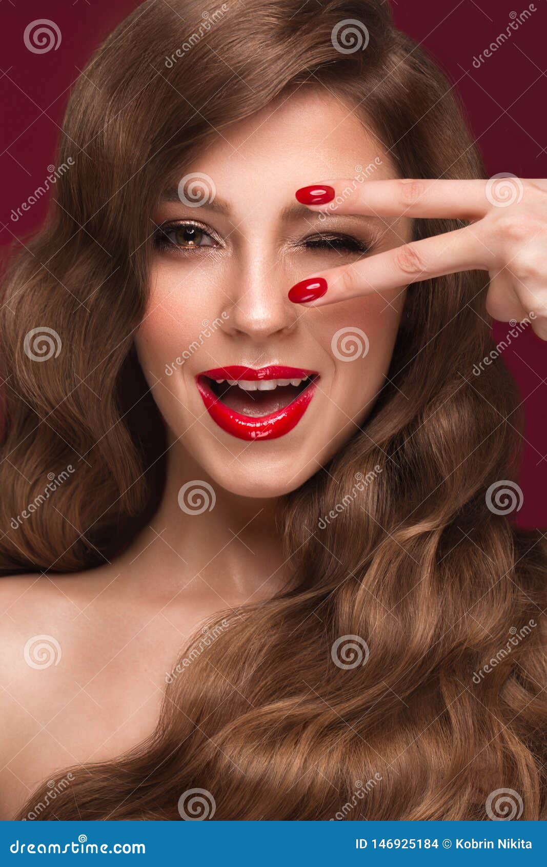 Beautiful girl with a classic makeup, curls hair and red nails. Manicure design. Beauty face. Beautiful girl with a classic make up, curls hair and multi-colored nails. Manicure design. Beauty face. Photo taken in the studio