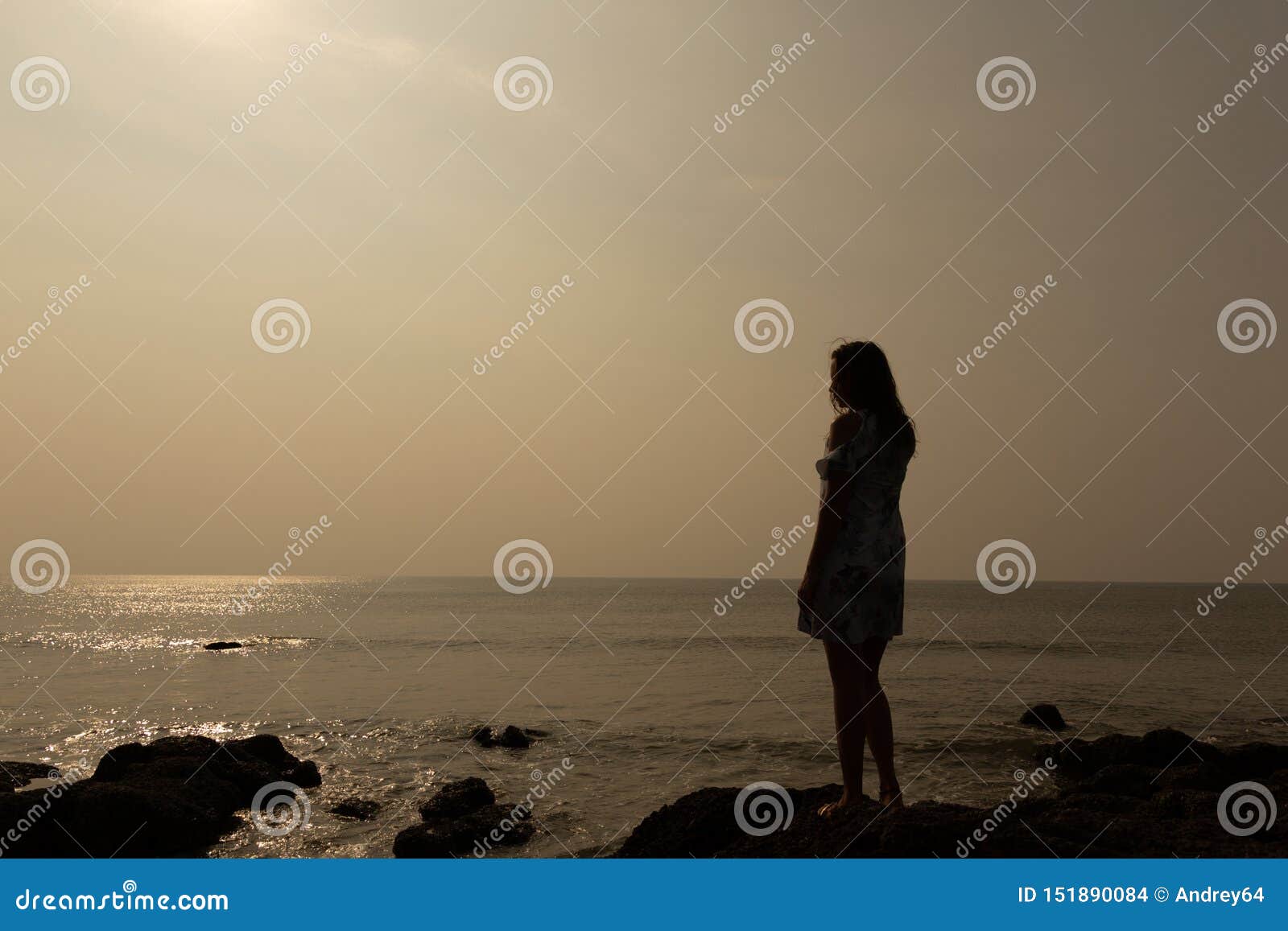 Schattenbild einer jungen Frau vor dem hintergrund des Meeres und der Sonne