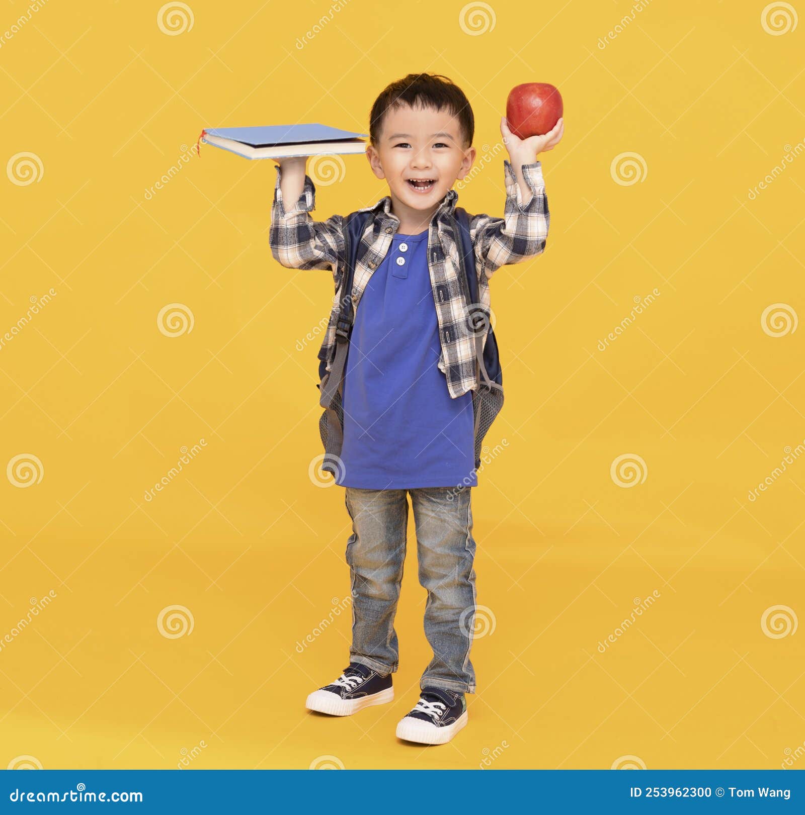 school boy with bagpack hold apple and book  on yellow