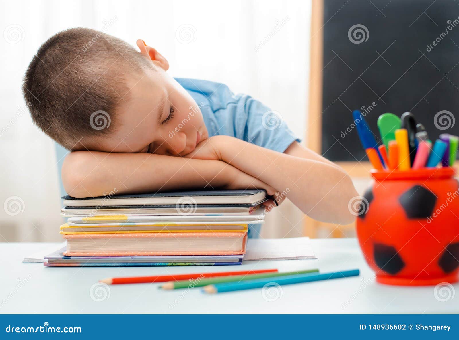 school boy sitting at home classroom lying desk filled with books training material schoolchild sleeping lazy bored