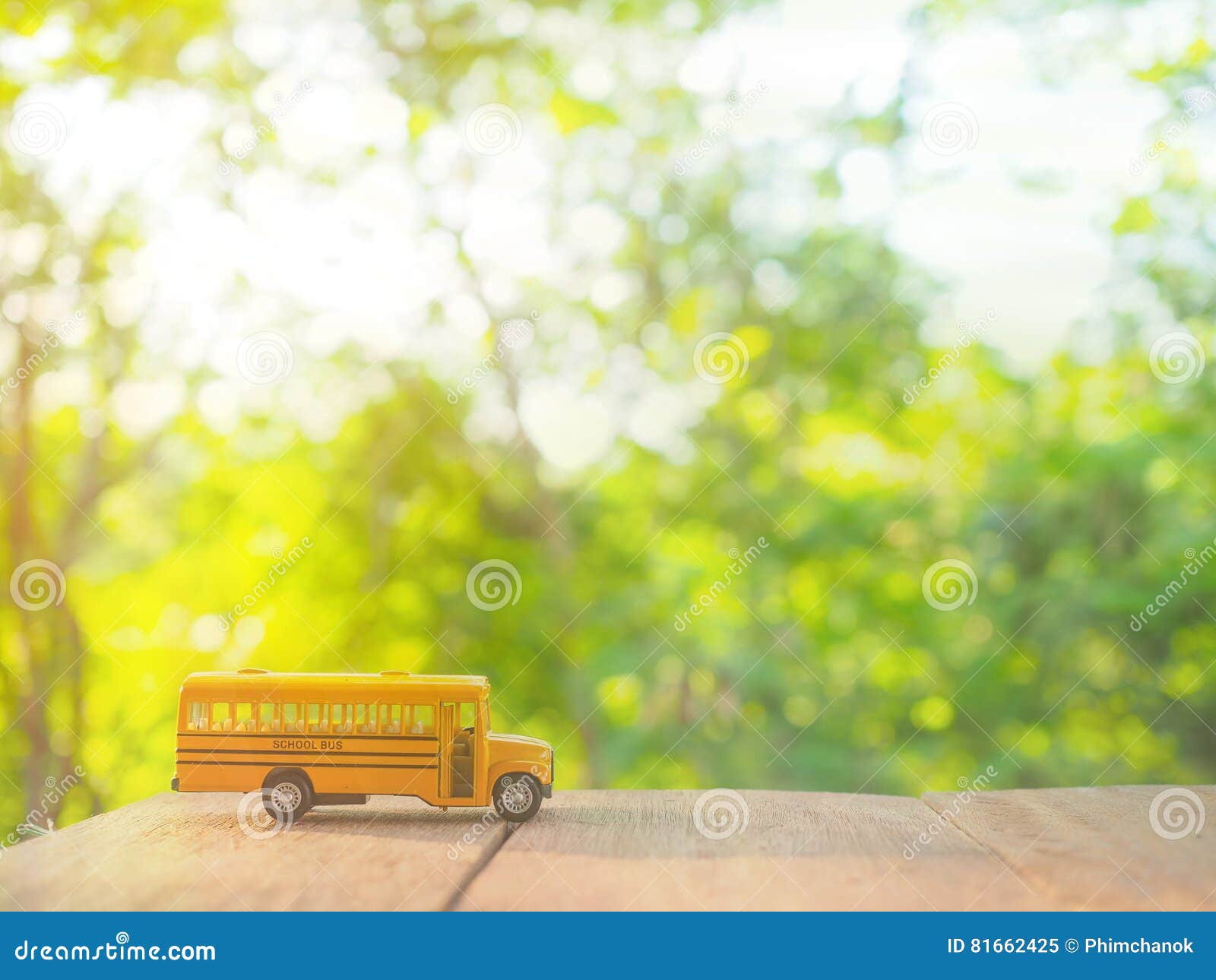 Yellow school bus plastic and metal toy model on the natural background and sunrise