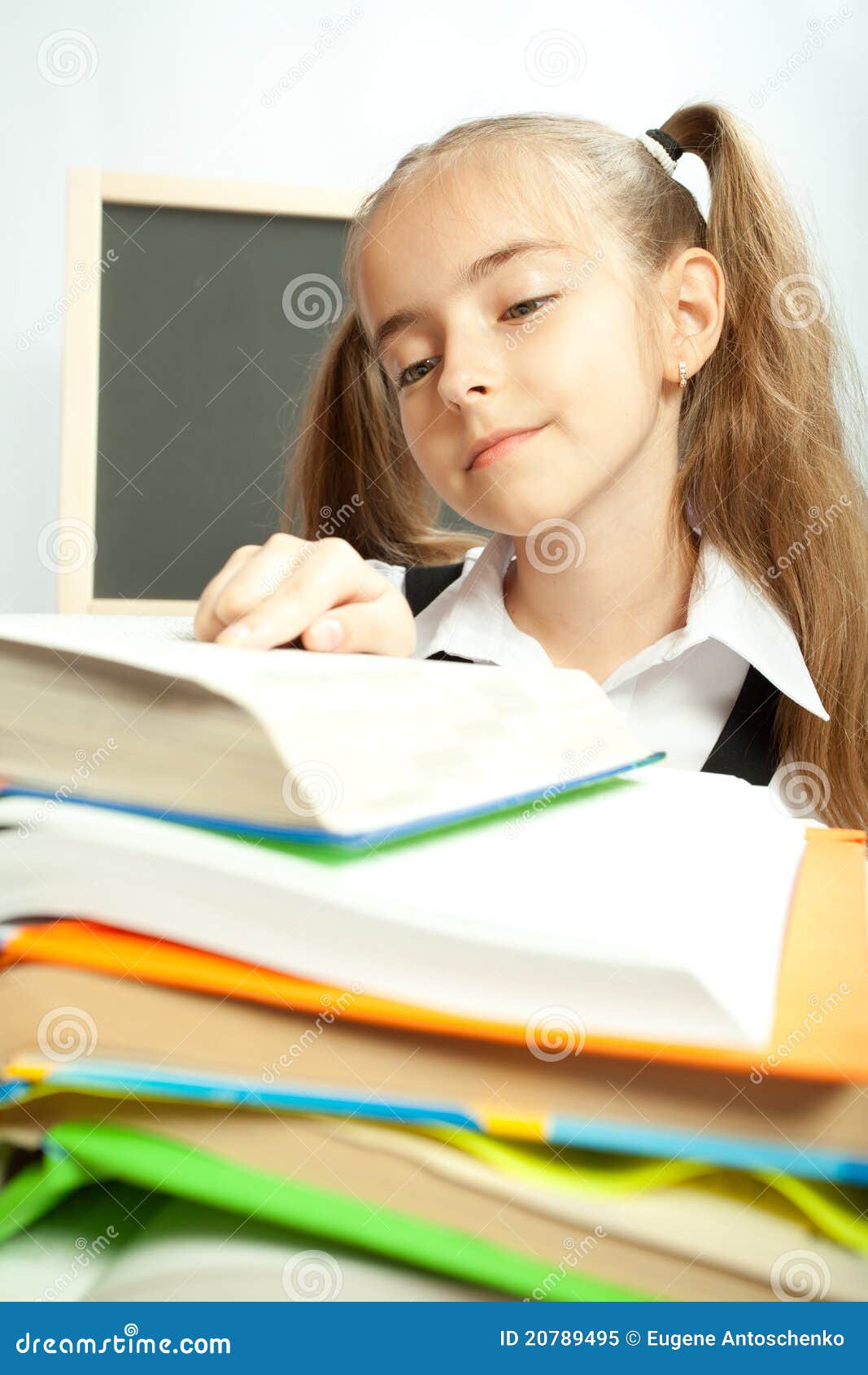 School girl making homework behind stack of books. Over light background