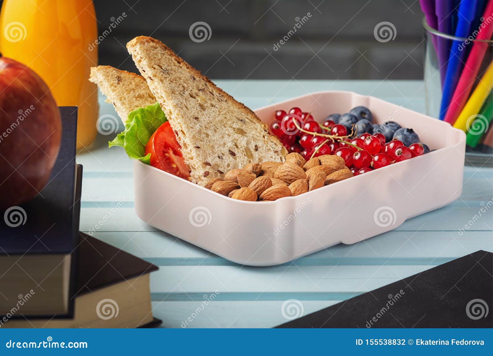 school lunch in a box, berries, nuts and a sandwich. almonds, red currants and blueberries for a child s snack. healthy