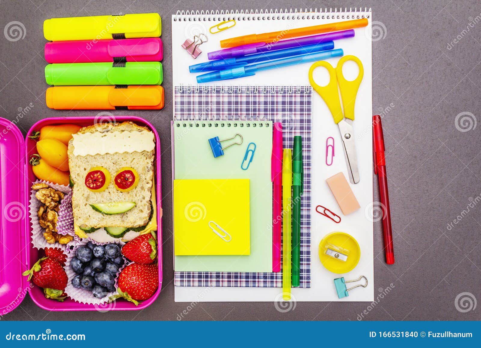 School supplies and lunch box with sandwich and vegetables. Back