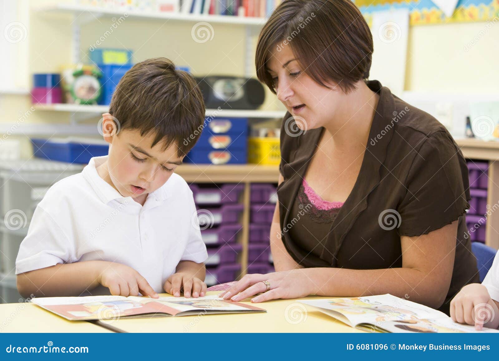 a schoolboy and his teacher reading in class
