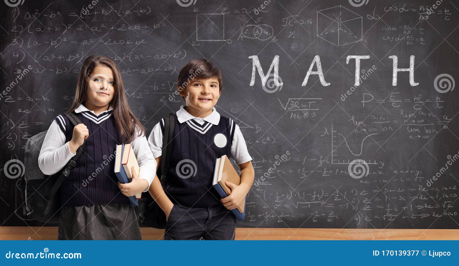 Schoolboy and Schoolgirl in Uniforms Standing in Front of a Chalkboard