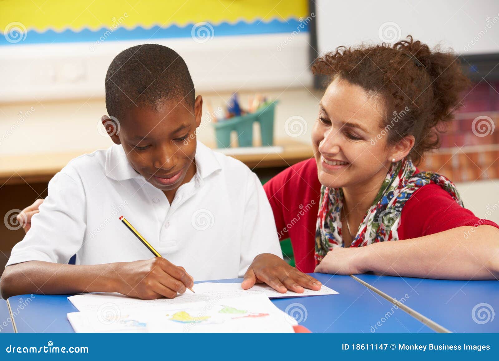 schoolboy studying in classroom with teacher