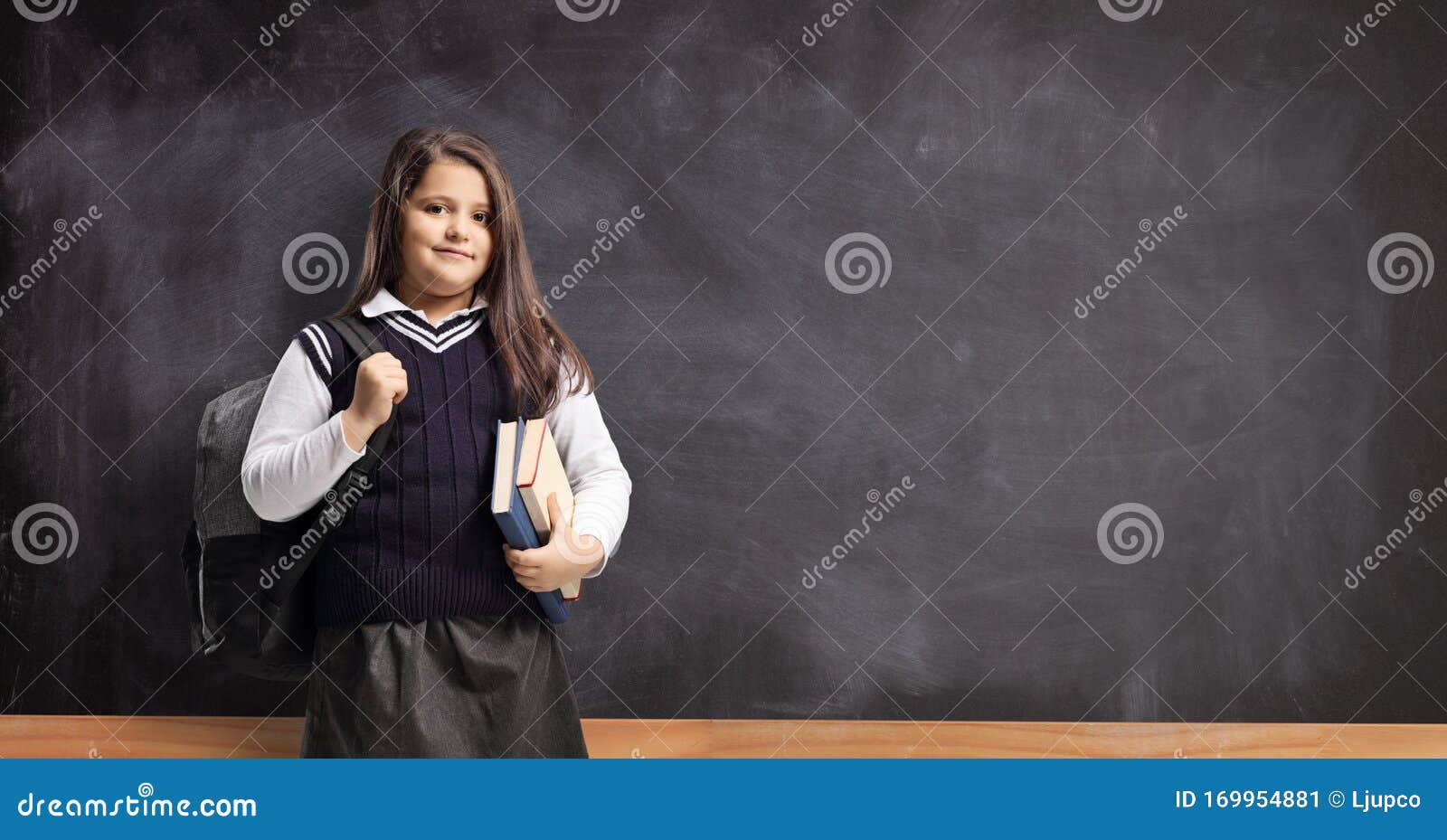 Schoolgirl in a Uniform Standing in Front of a Chalkboard Stock Image