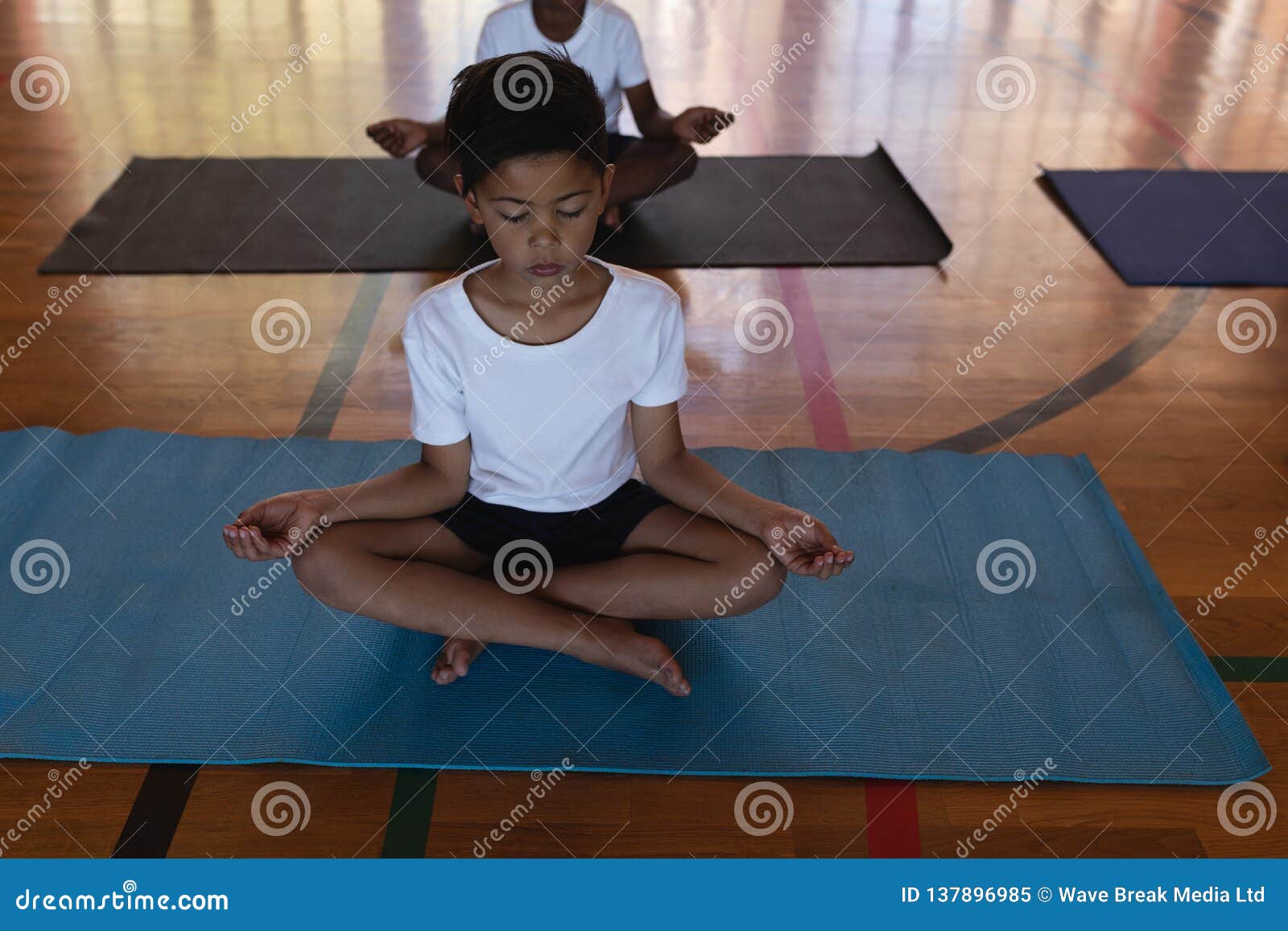 Schoolkids Doing Yoga and Meditating on a Yoga Mat in School Stock
