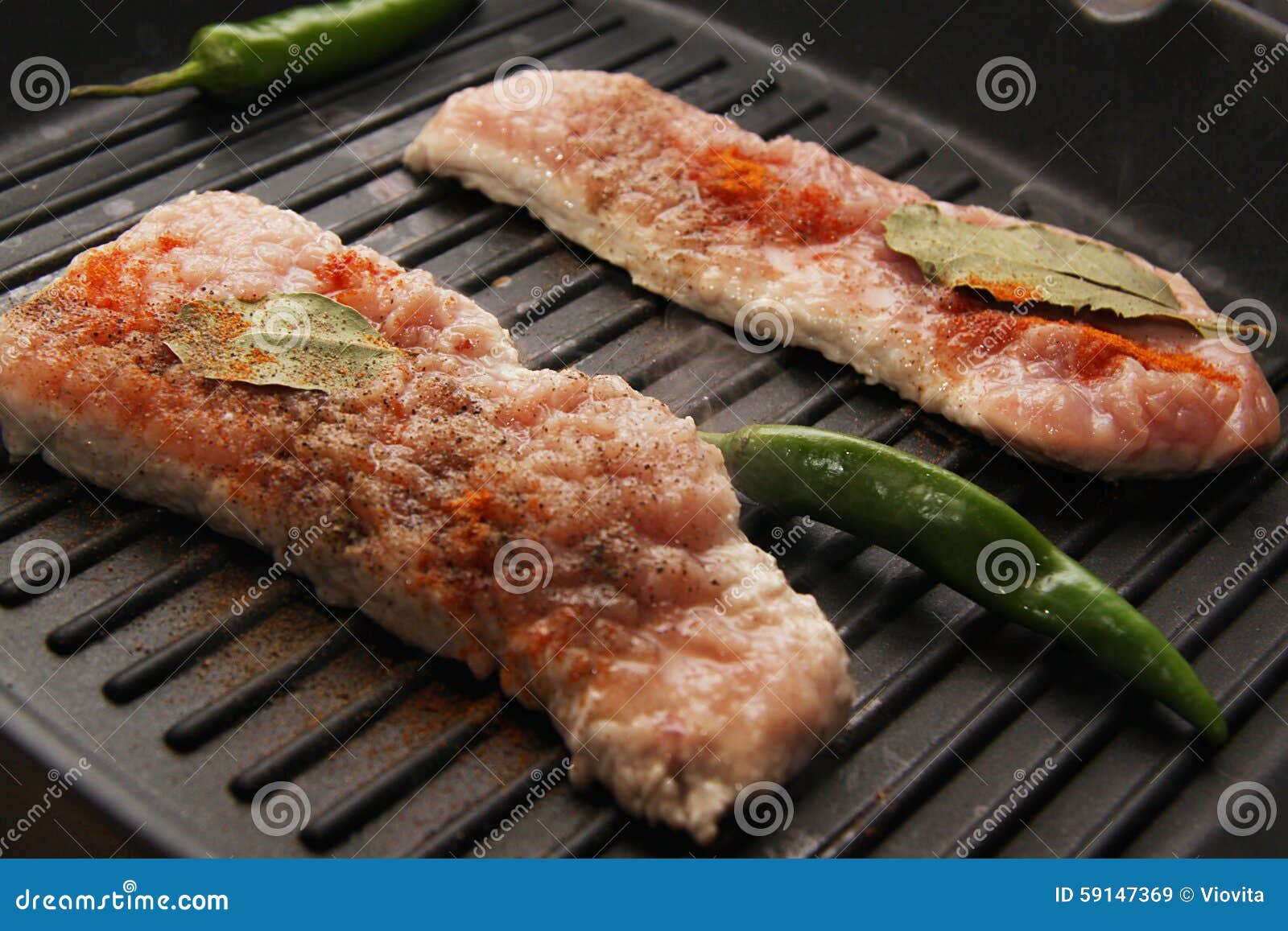 Schweinefleischsteaks auf Wanne. Prozess des Kochens von Schweinekoteletts mit Knoblauch und Kräutern