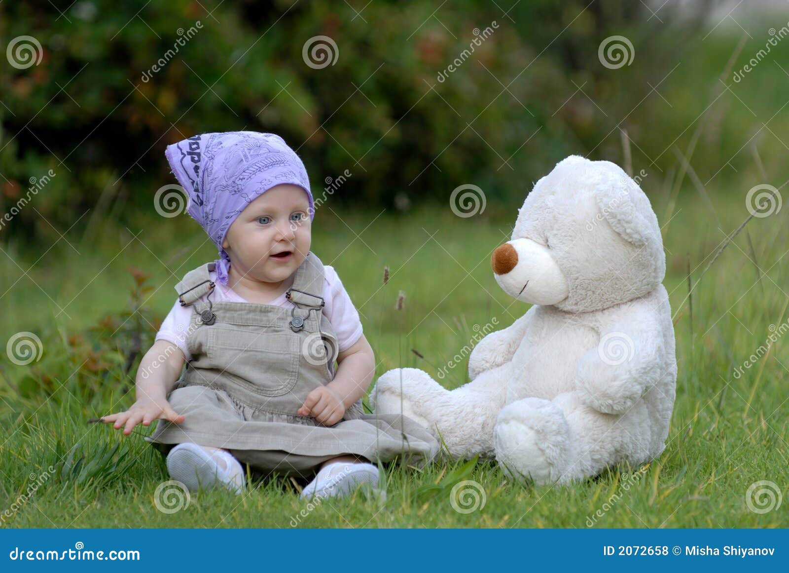 Schätzchen auf dem Gras mit einem Bärenspielzeug