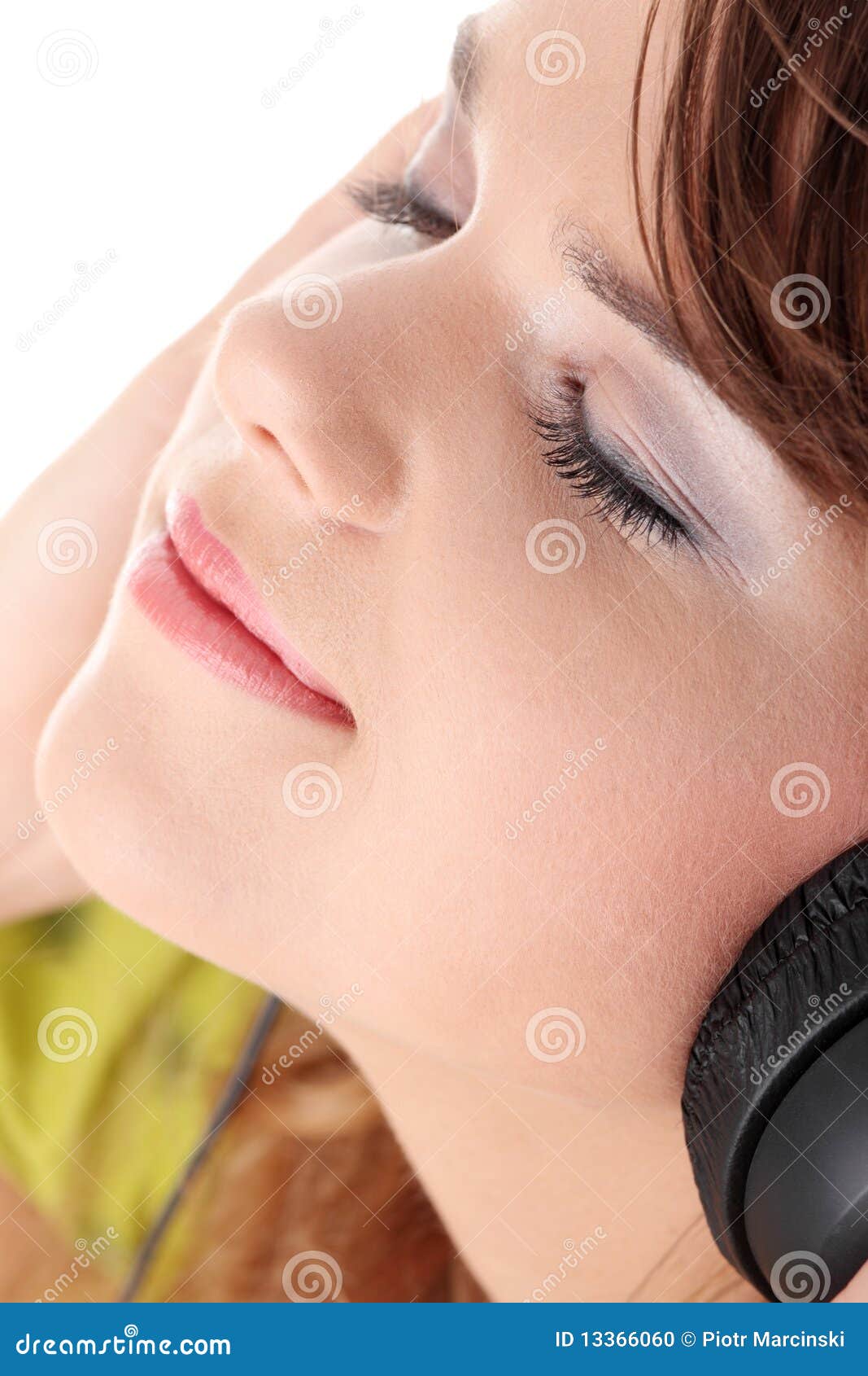 Schöne Jugendliche, die Musik hört. Schöne Jugendliche in einem grünen Kleid hörend Musik mit den großen Kopfhörern, getrennt auf Weiß