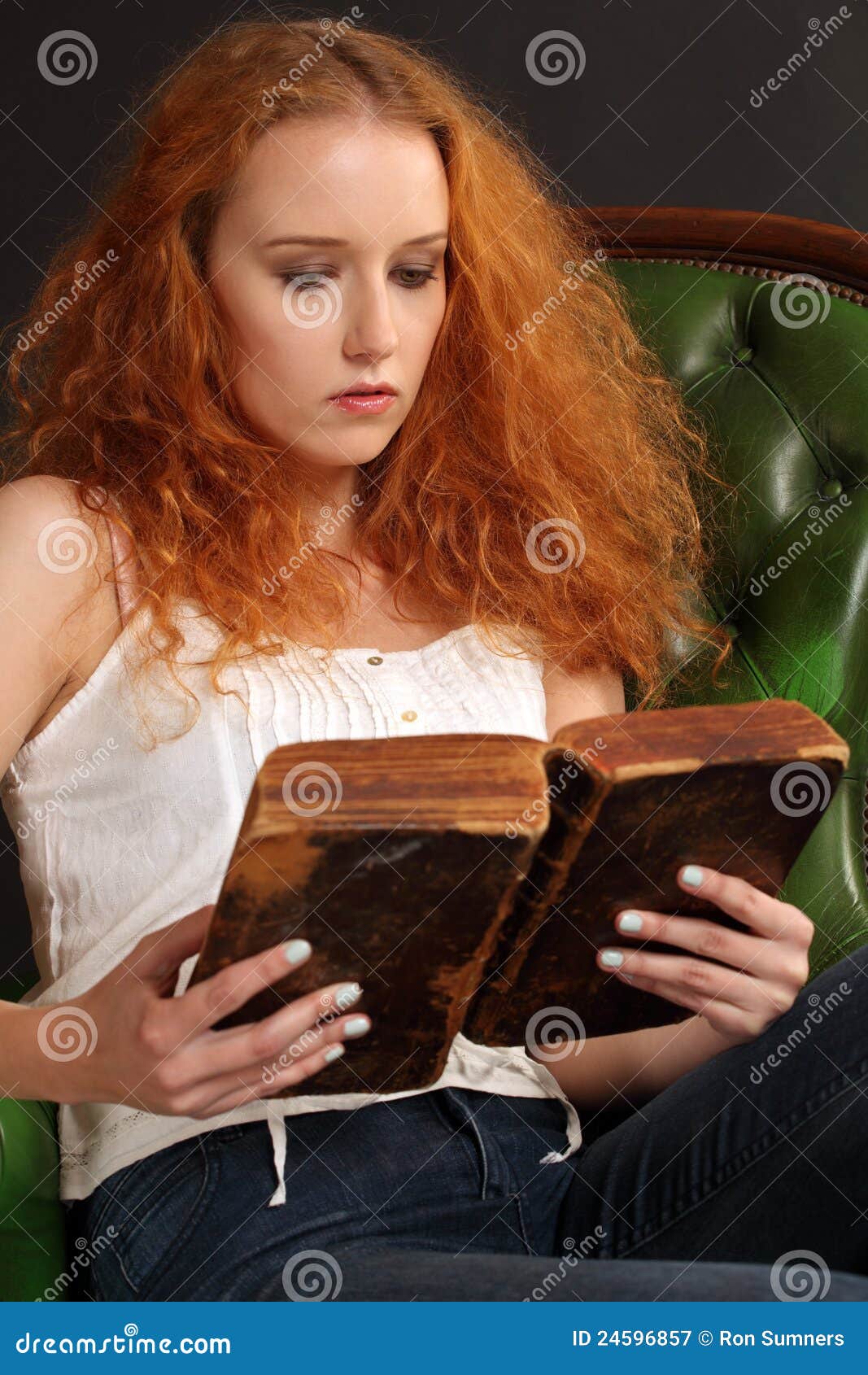 Schöner Redhead, der eine Bibel liest. Foto einer schönen Redheadfrau, die eine alte Bibel von 1786 liest.