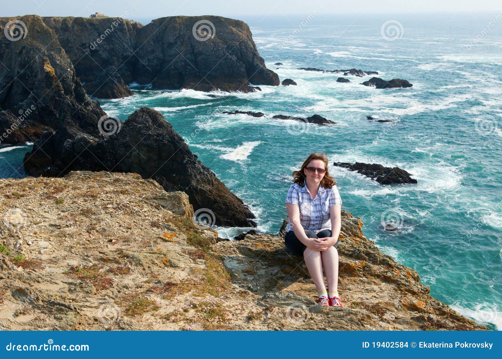 Schönes junges Mädchen, das auf einem Felsen sitzt. Schönes junges Mädchen, das auf einem Felsen am Belle-Ile-en-mer, Bretagne, Frankreich sitzt