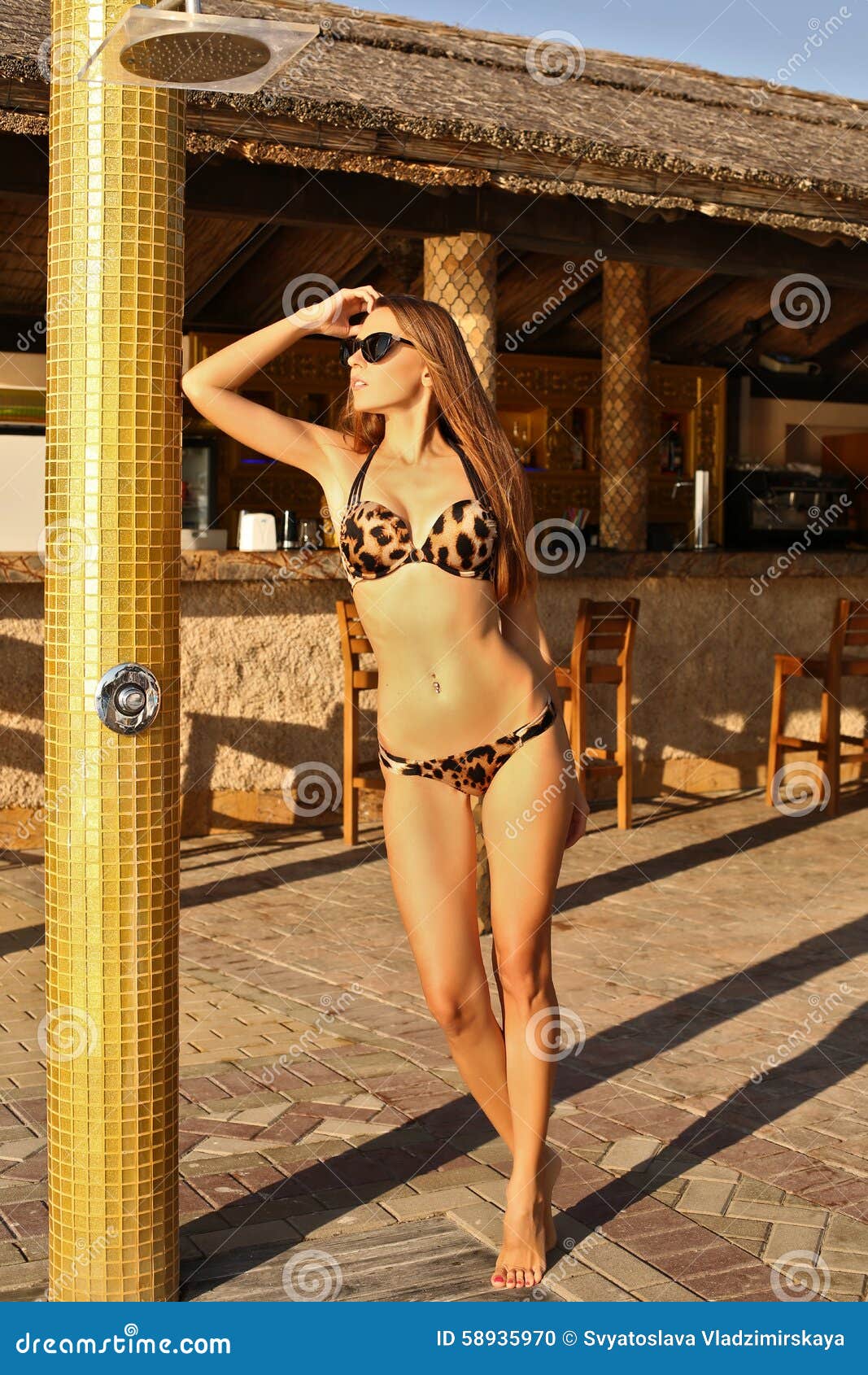 Schönes sinnliches Mädchen mit dem dunklen Haar trägt eleganten Badeanzug. Foto der Mode im Freien des schönen sinnlichen Mädchens mit dem dunklen Haar trägt den eleganten Badeanzug und wirft neben Swimmingpool auf