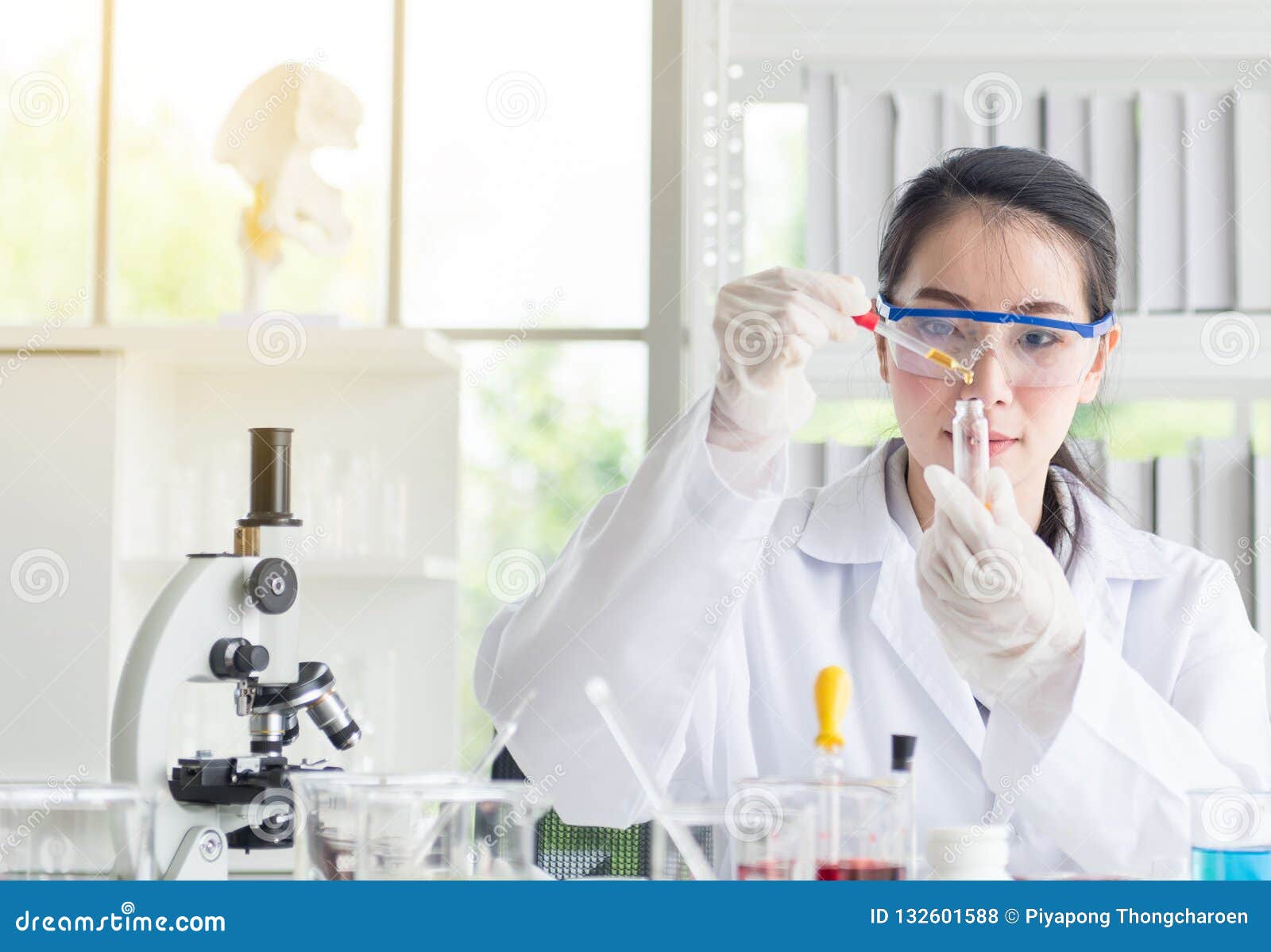 Scientist beautiful woman research and drop medical chemicals sample in test tube at lab. Scientist beautiful woman research and drop medical chemicals sample in test tube at lab