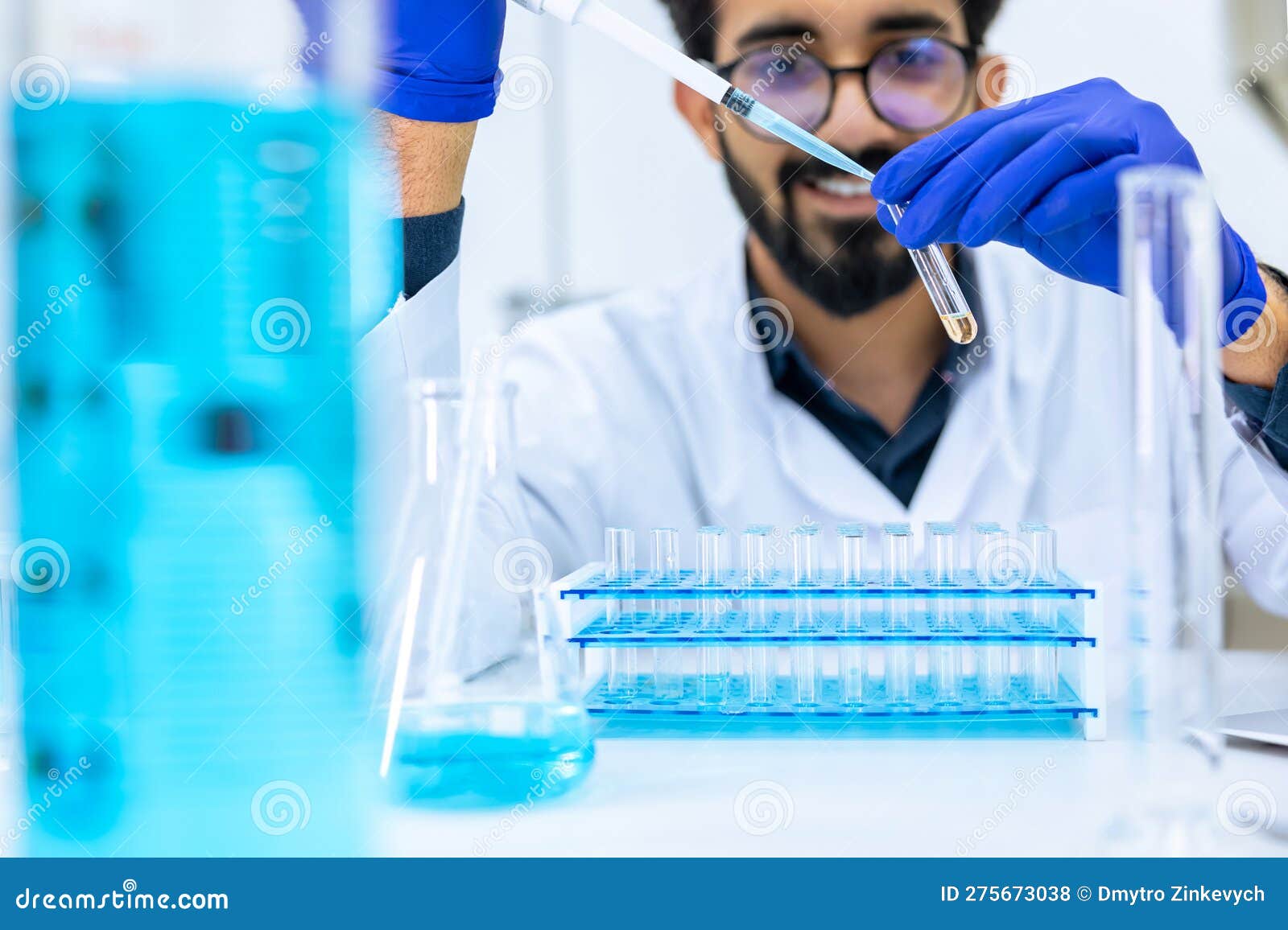 scientist man testing chemical sample in flask at laboratory with lab glassware.