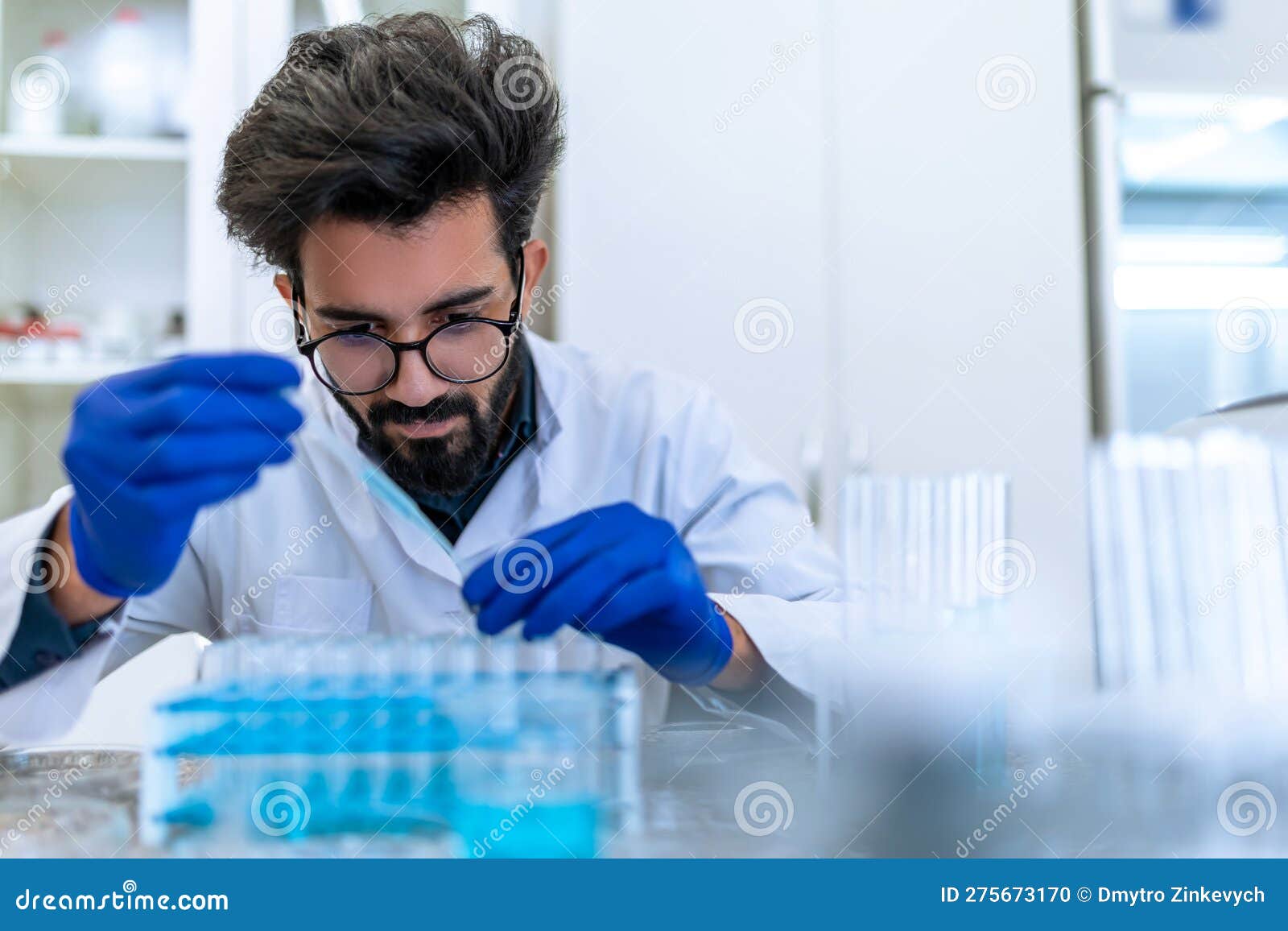 scientist man testing chemical sample in flask at laboratory with lab glassware.