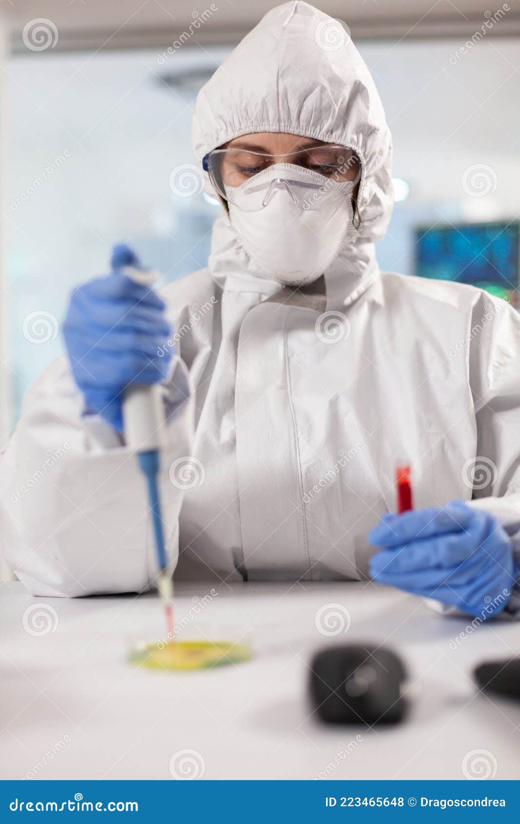 Scientist in Ppe Suit Analyzing Blood Sample on Petri Dish Stock Photo