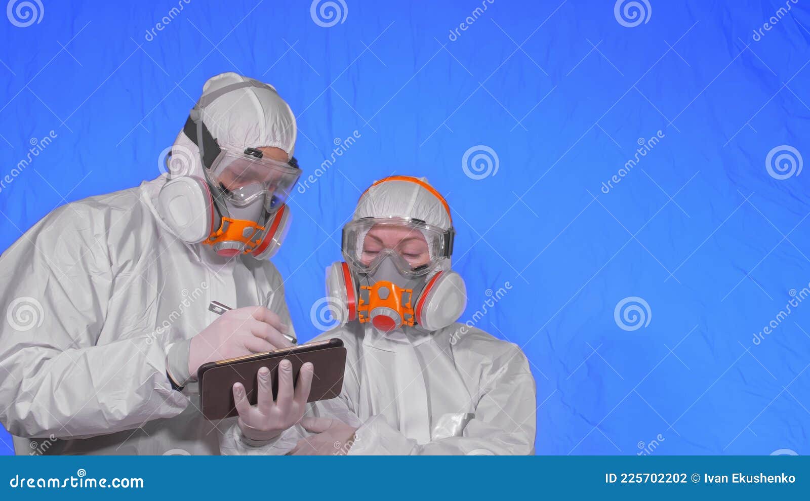scientist virologist in respirator makes write in an tablet computer with stylus. man and woman wearing protective