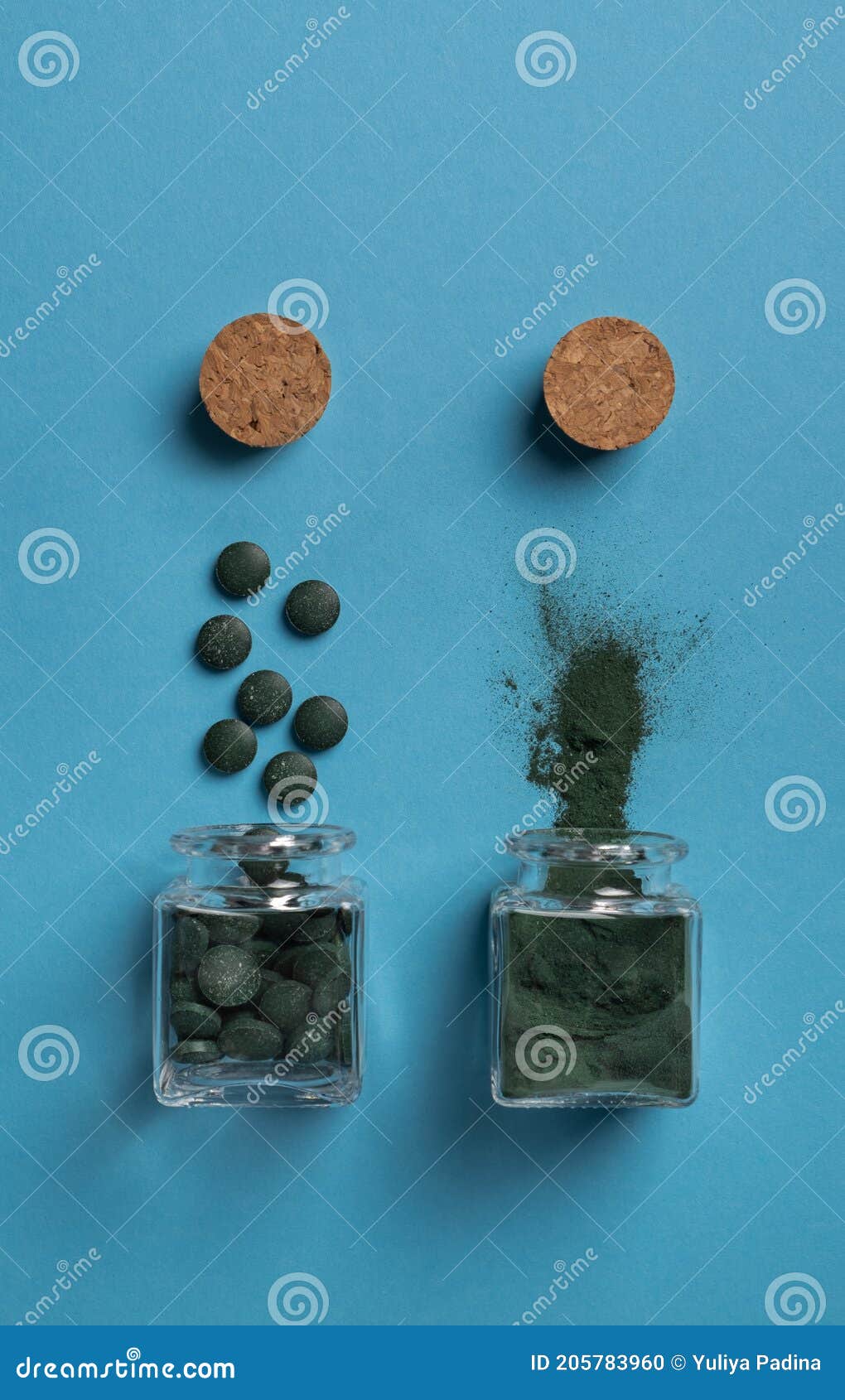 Spirulina Algae Powder and Chlorella Tablets in Glass Jars on a Blue