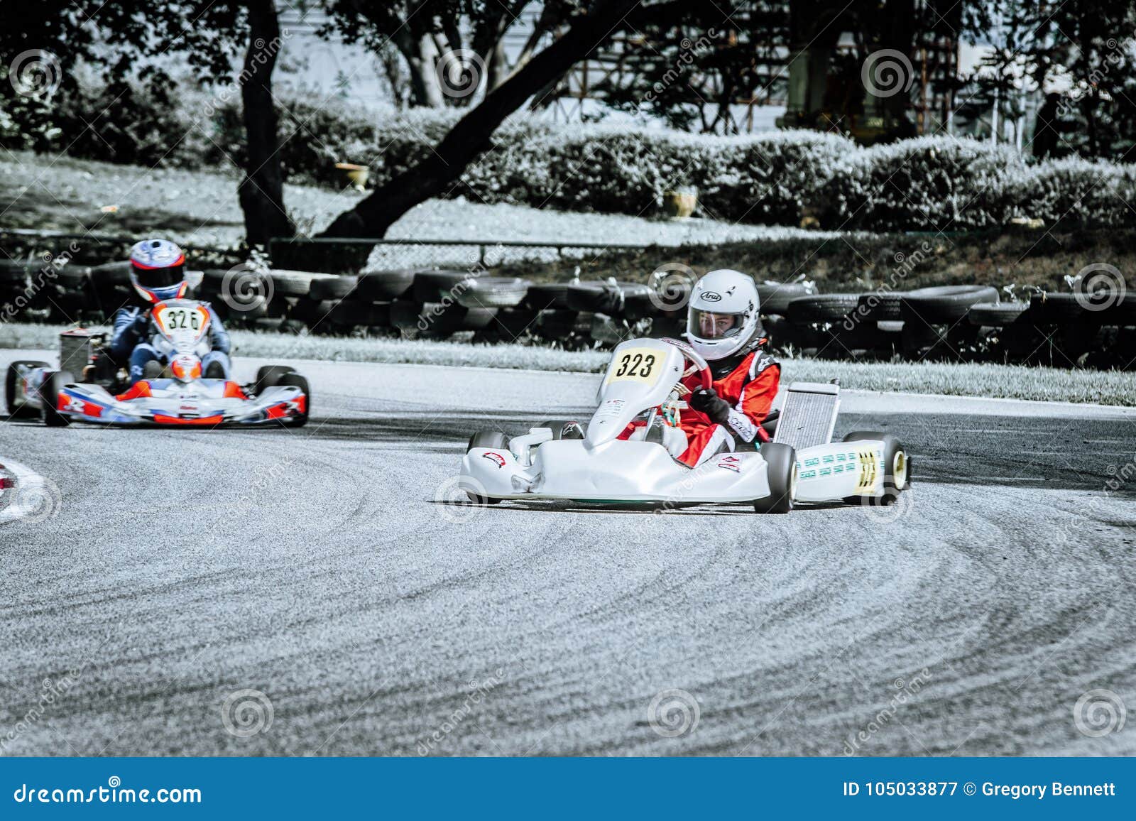 Scorrevole di vista frontale 326 di Karting 323. Kart 323 di corsa in uno scorrevole mentre inseguimento 326 nei colori scoloriti