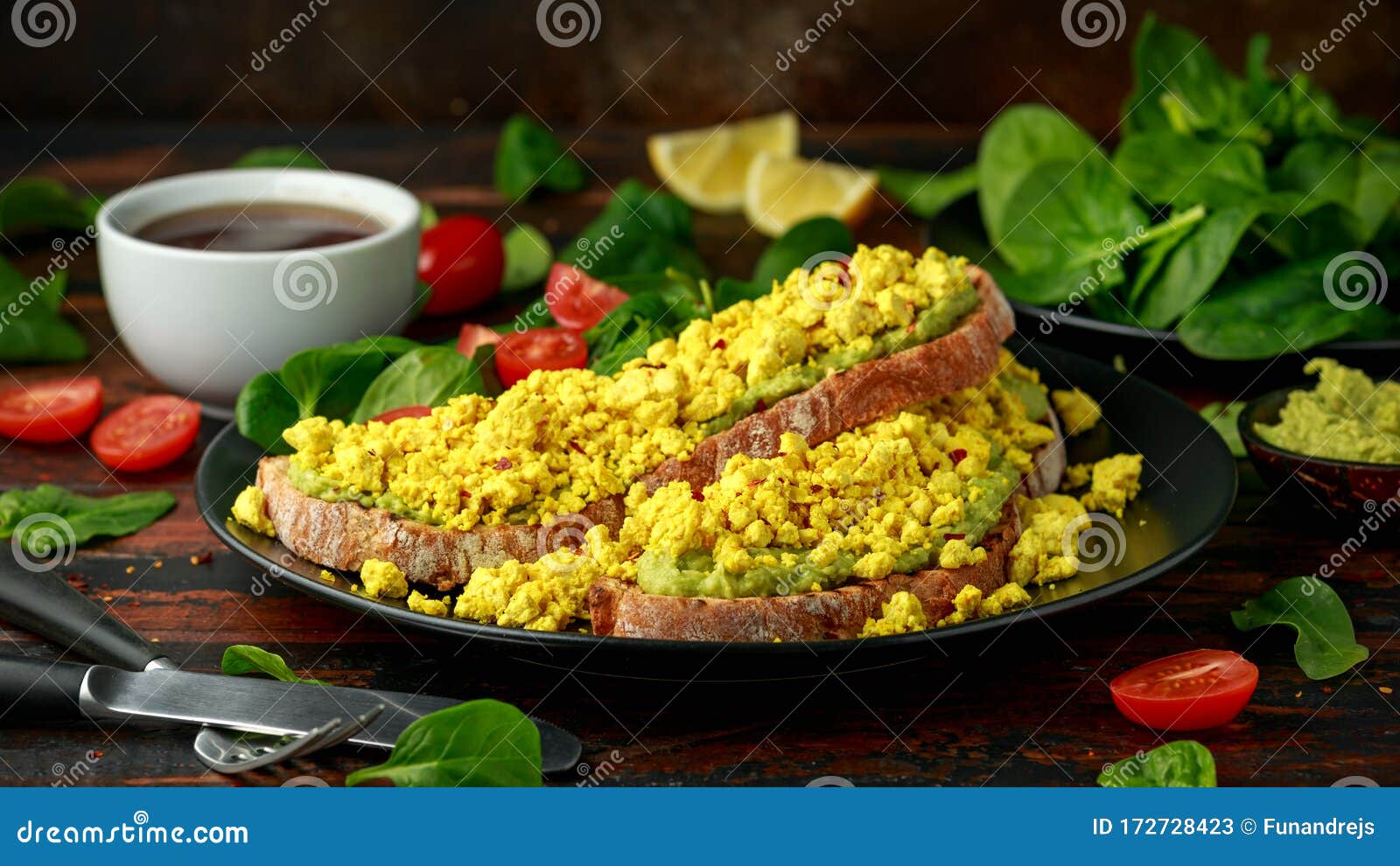 scrambled tofu crispy toast with guacamole and spinach, tomato salad. vegan vegetarian, plant based food