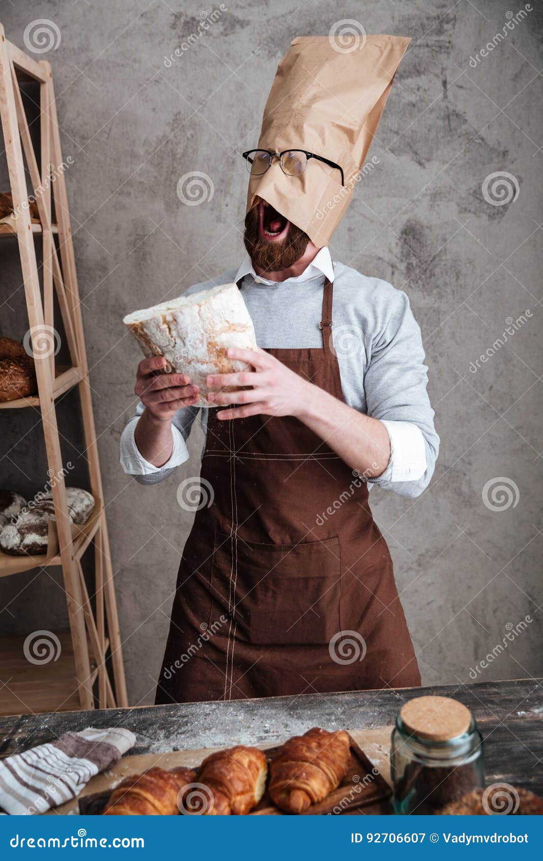 Cheerful young man baker standing at bakery holding bread Stock Photo by  vadymvdrobot