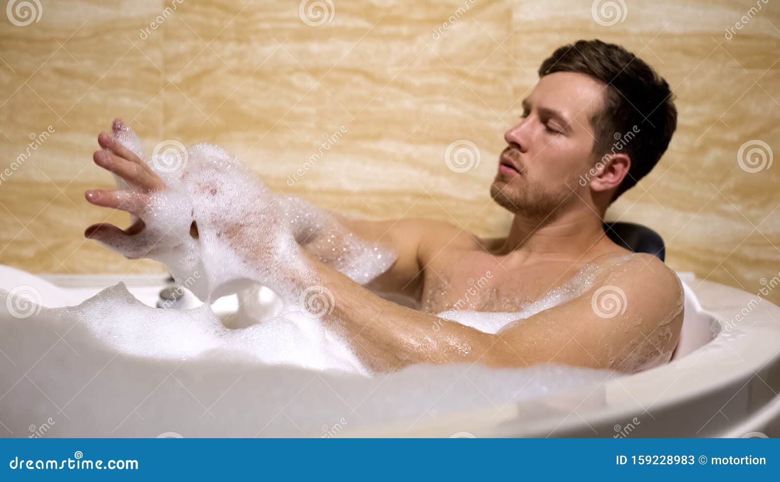 scrupulous man soaping himself with loofah, taking bath with foam, cleanness