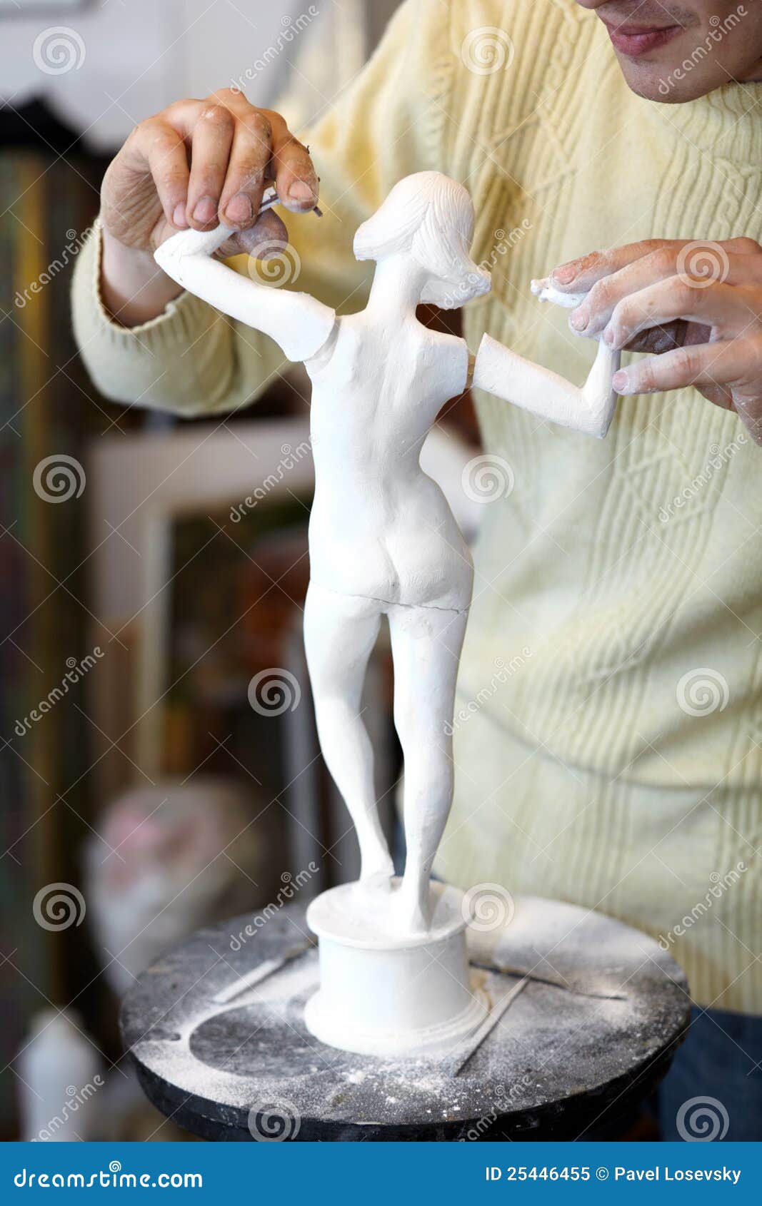 sculptor attach arms to armless statuette.