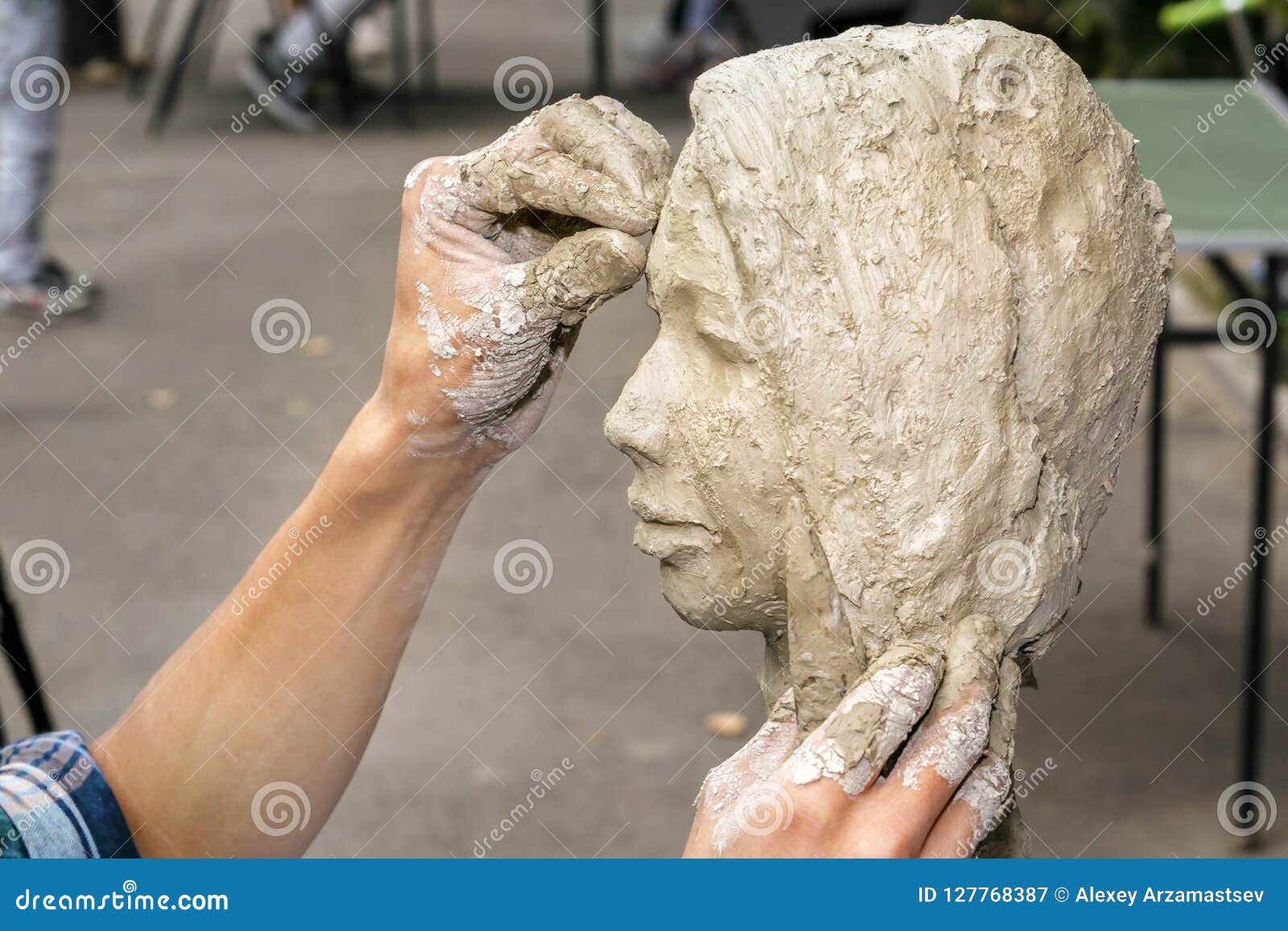 sculptor creates a bust and puts his hands clay on the skeleton of the sculpture.