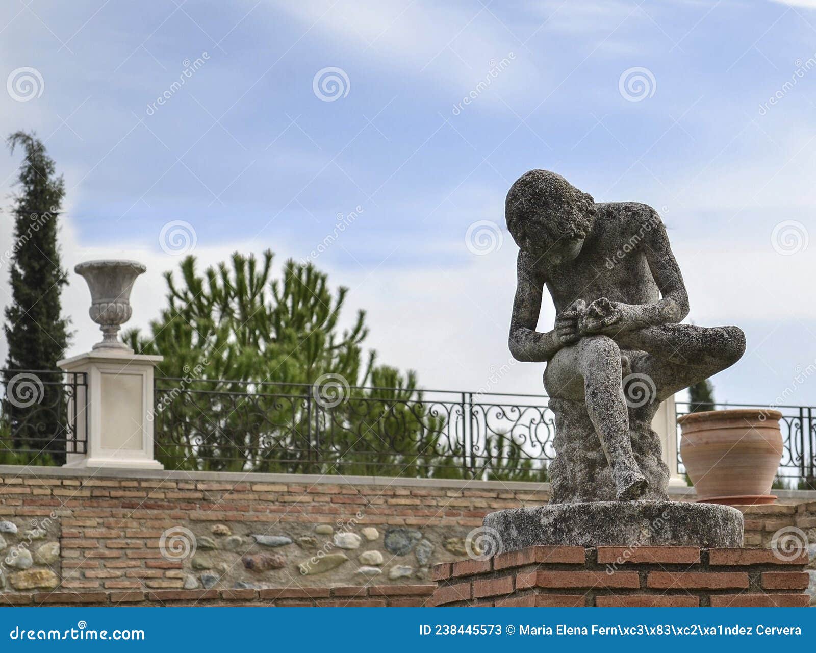 sculpture of a boy sitting while removing a thorn from the sole of his left foot in the quinta alegre palace in granada