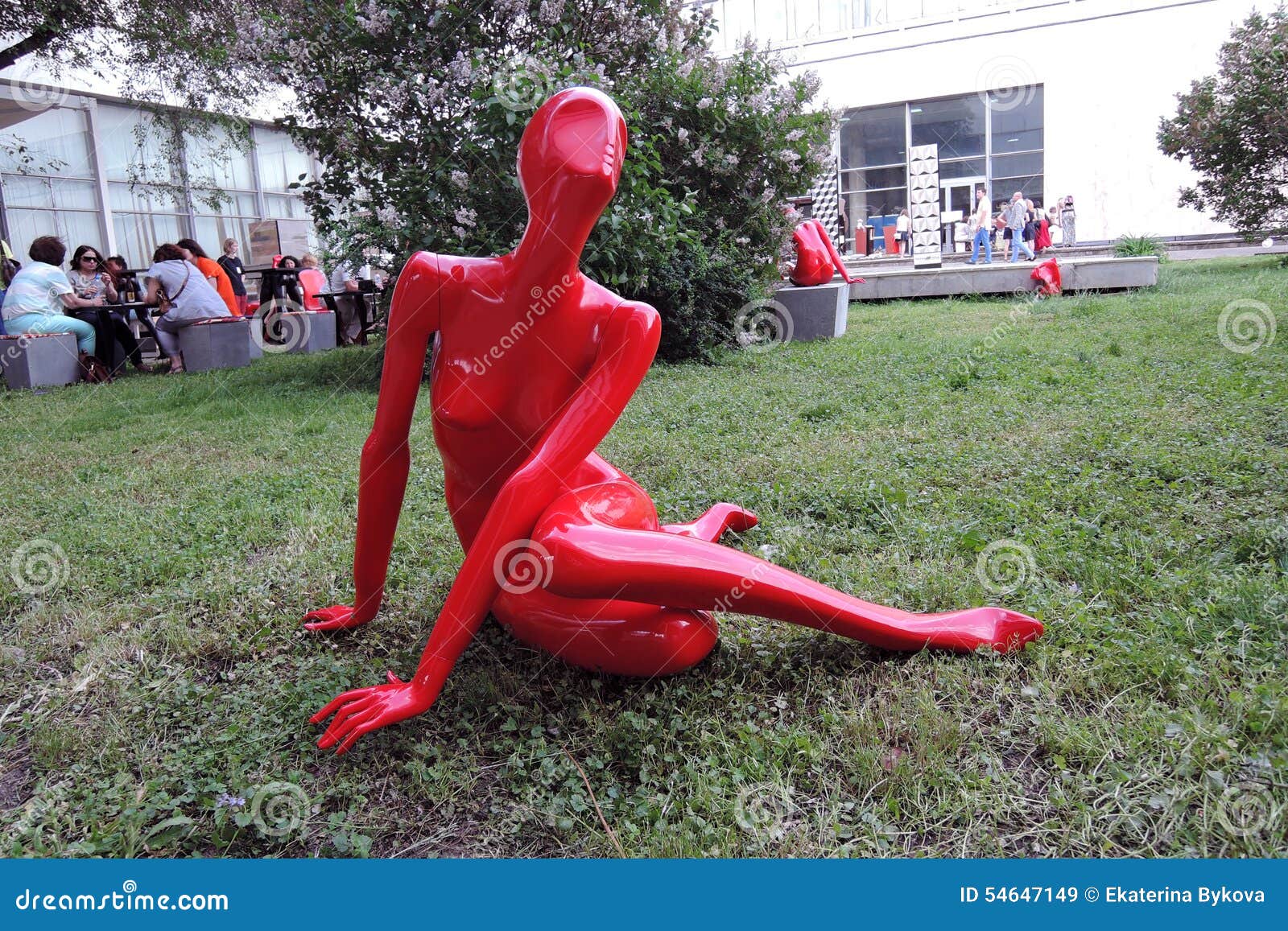 MOSCA - 27 MAGGIO 2015: Scultura di plastica rossa della donna Si siede sul campo di erba verde XX mostra dell'internazionale di architettura e di progettazione ArchMoscow 2015 Uno degli eventi annuali principali nel campo architettonico di affari Posizione: Camera centrale degli artisti, Mosca, Russia