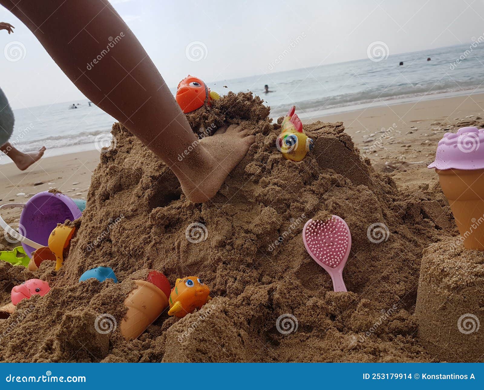 sea beach castle of sand made by children with toys on it by t