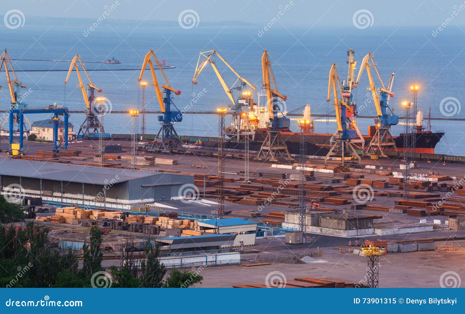 sea commercial port at night in mariupol, ukraine. industrial view. cargo freight ship with working cranes bridge in sea port at