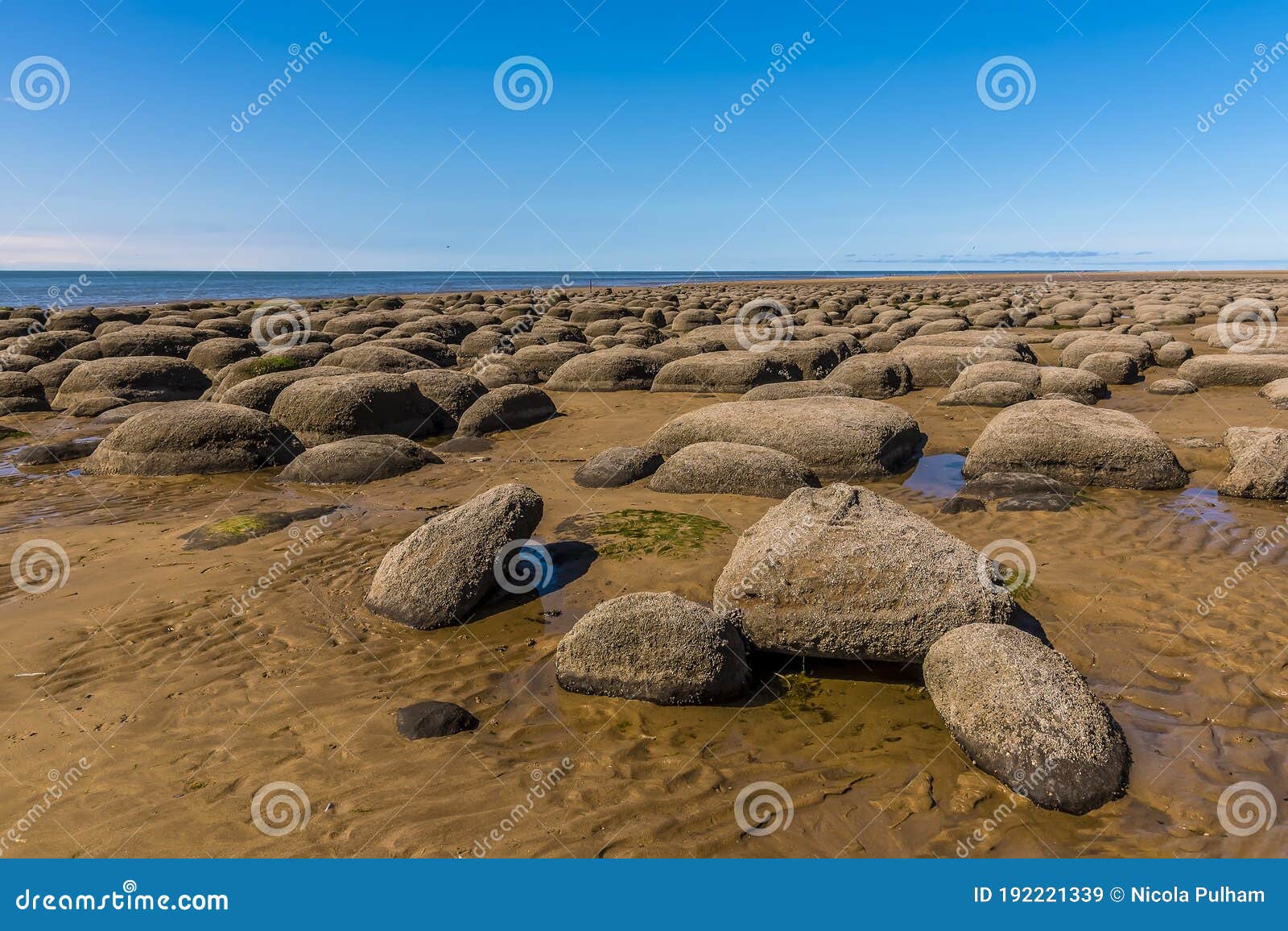 sea eroded boulders protrude from the sand at old hunstanton beach, norfolk, uk