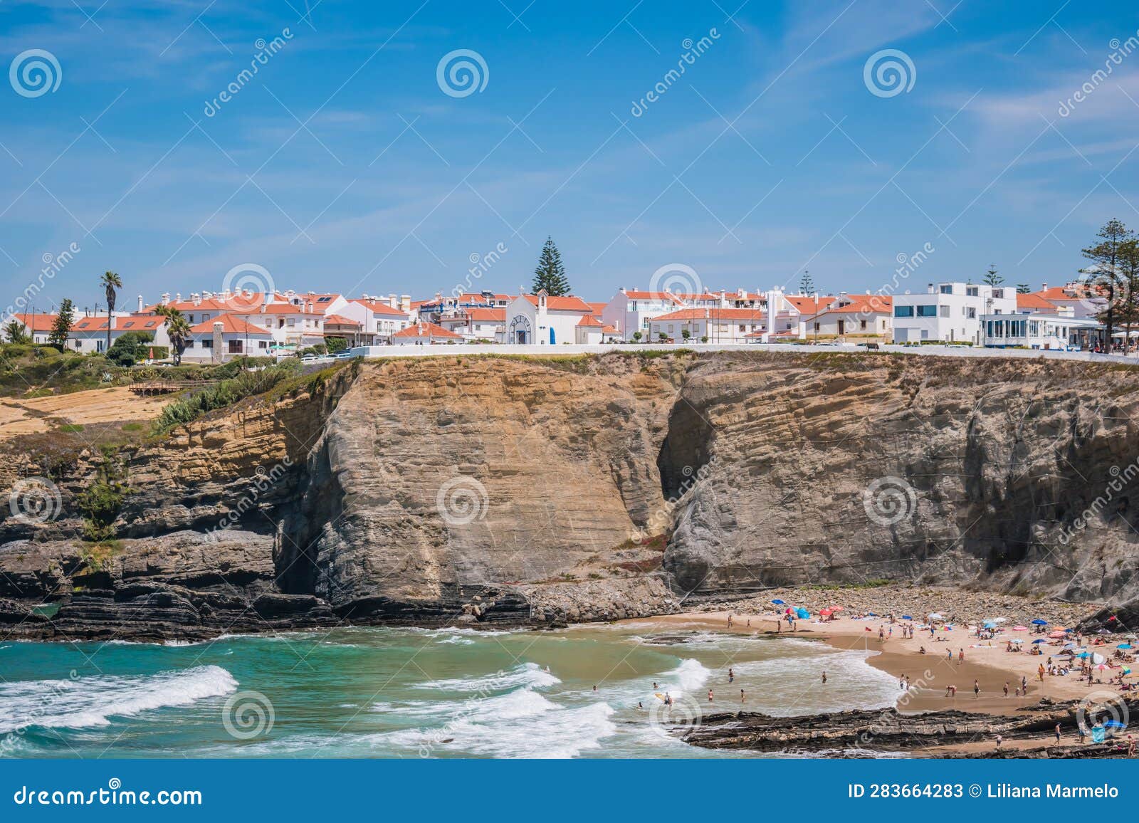 sea and waves on zambujeira do mar beach with village architecture on top of cliff, odemira - alentejo portugal