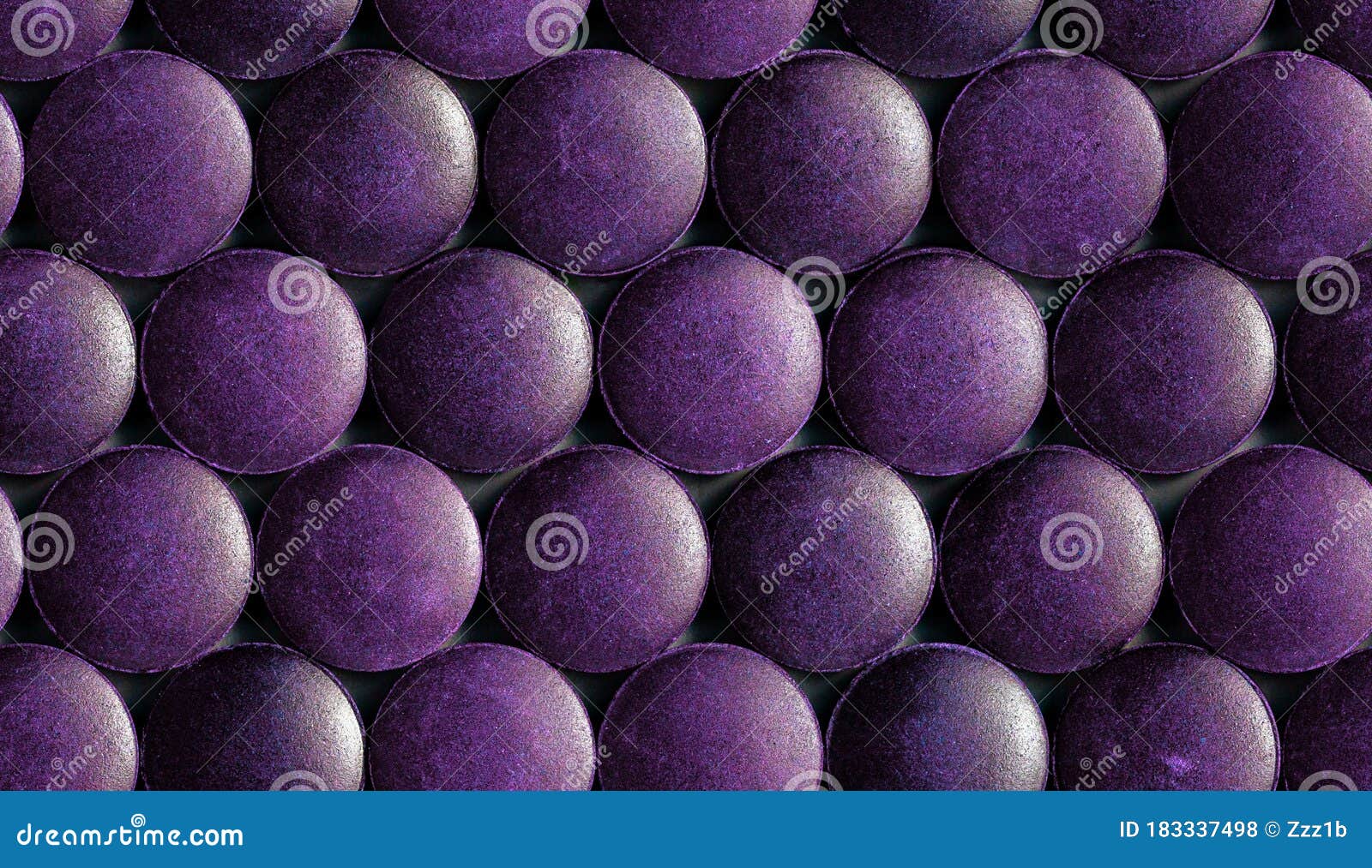 a seamless hexagonal pattern of many purple organic spirulina tablets laid tight in one layer on flat surface