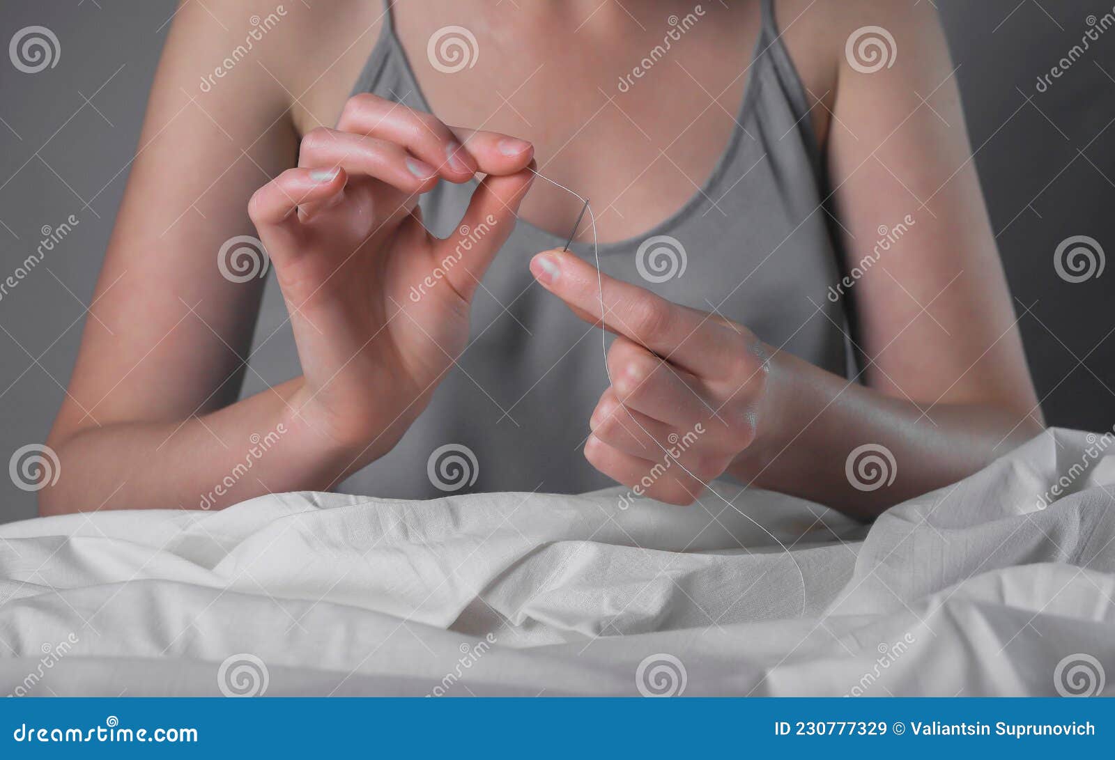 Seamstress Hands Inserting Thread into Needle Hole for Manual Sewing