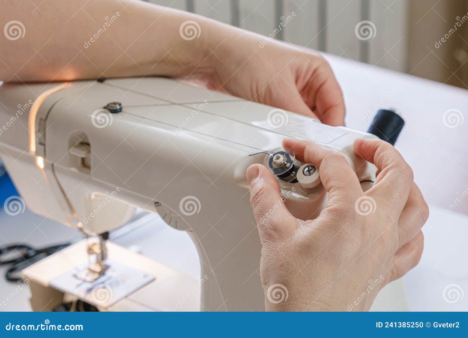 Seamstress Winds Thread on the Bobbin of an Electric Sewing Machine