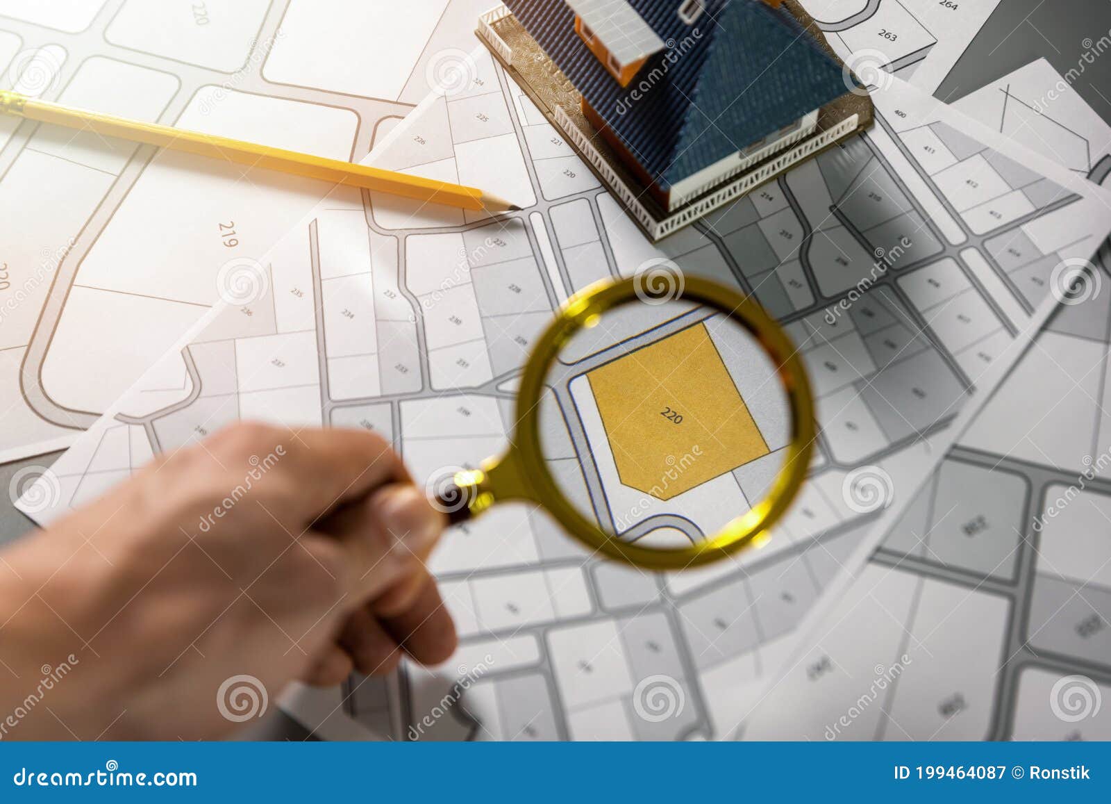 searching building plot for family house construction - hand with magnifier on cadastre map