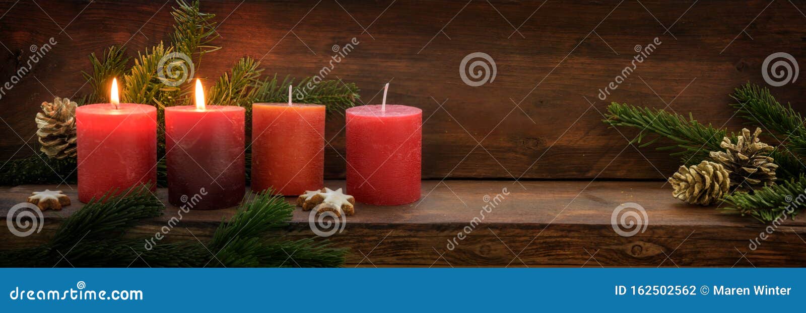 second sunday in advent, four red candles, two of them are burning, fir branches and christmas decoration on dark rustic wood,