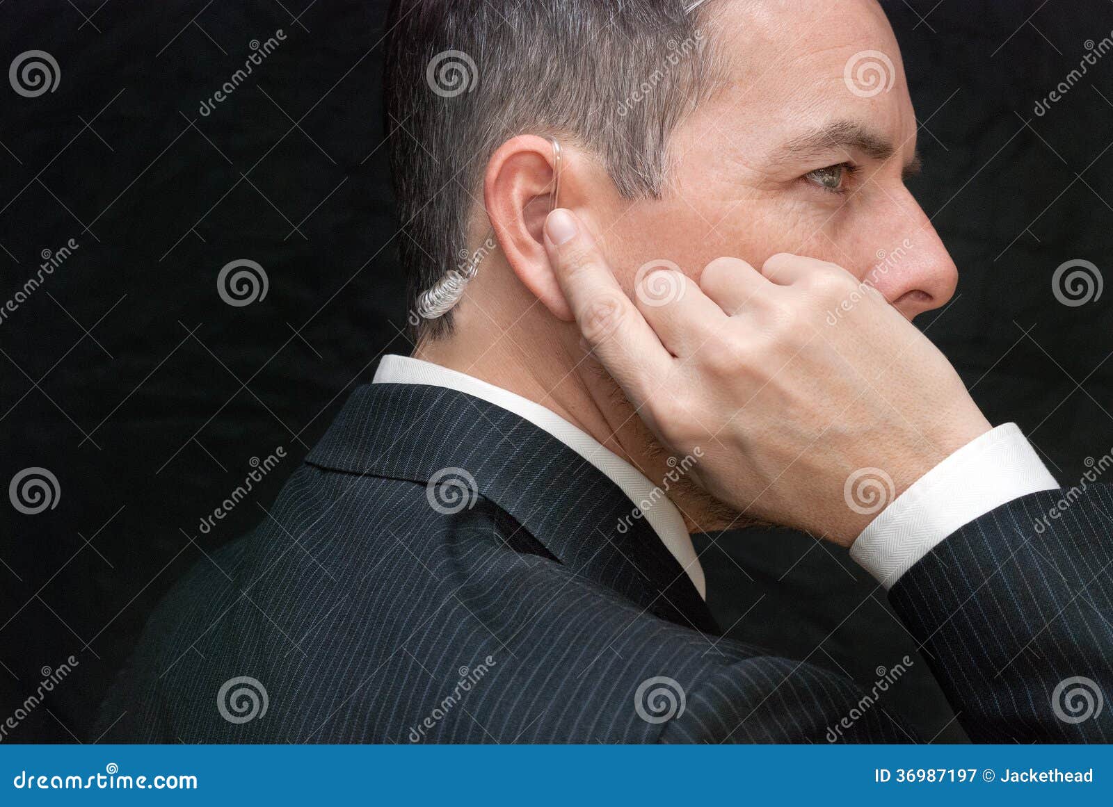 secret service agent listens to earpiece, side