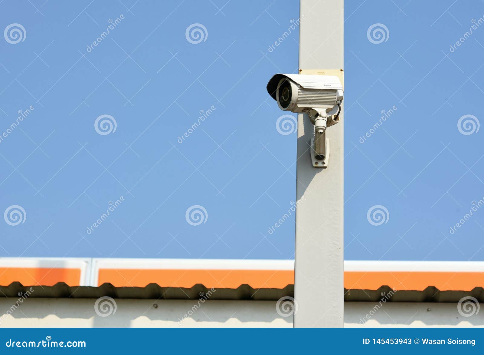 the security camera is on the pole above the roof of the house