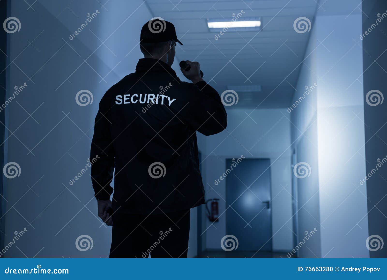security guard with flashlight in building corridor
