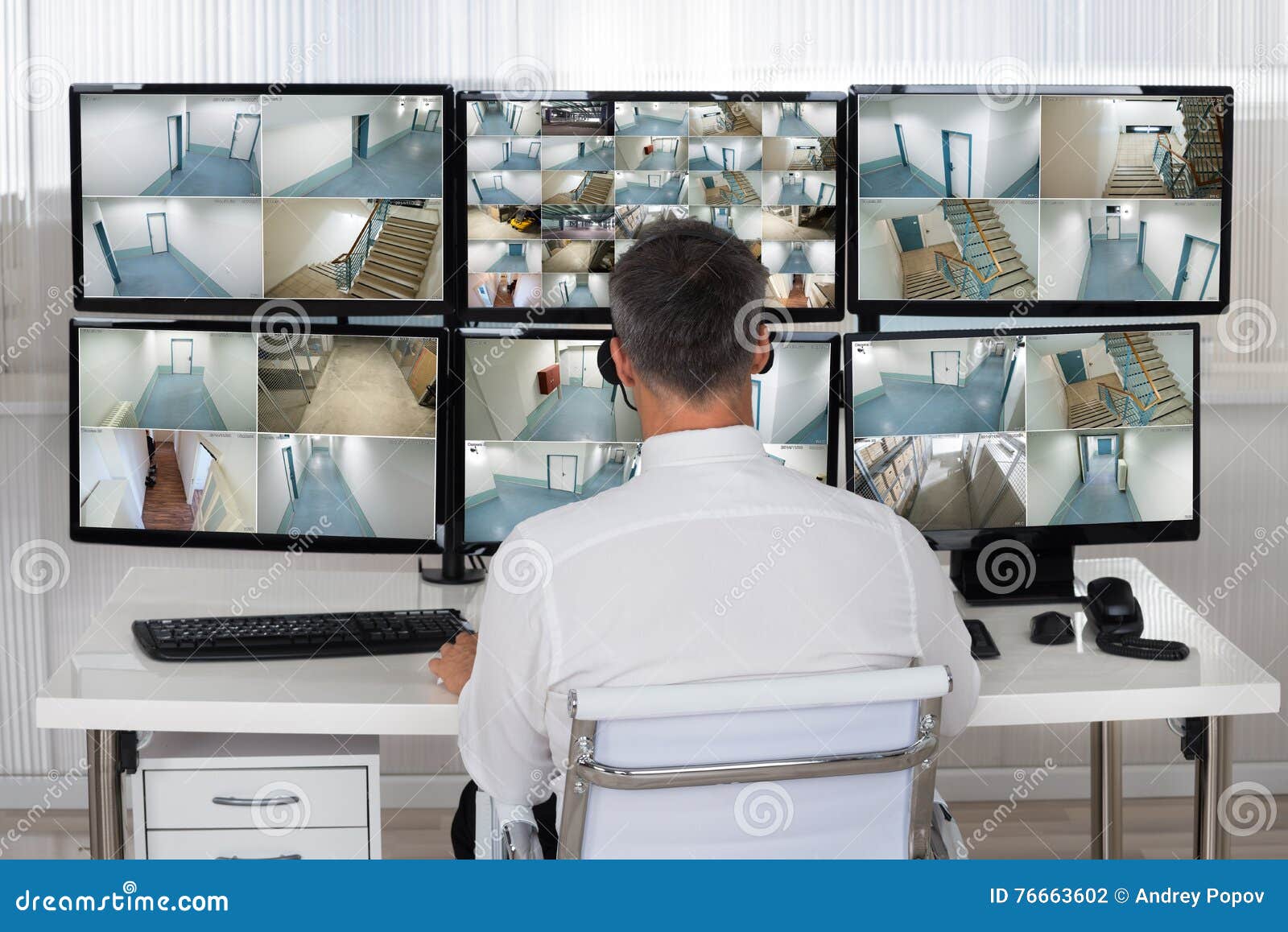 Security System Operator Looking at CCTV Footage at Desk Stock Photo